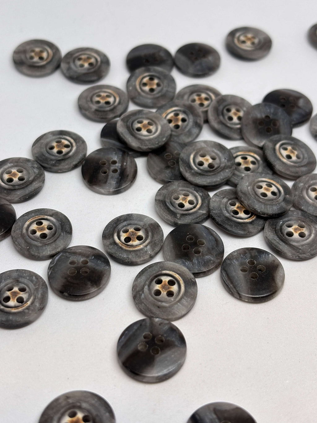 Botón 340MP Gris 4 Agujeros Plano 20mm con textura marmoleada tipo cuerno y detalle central de estrella oxidada. button