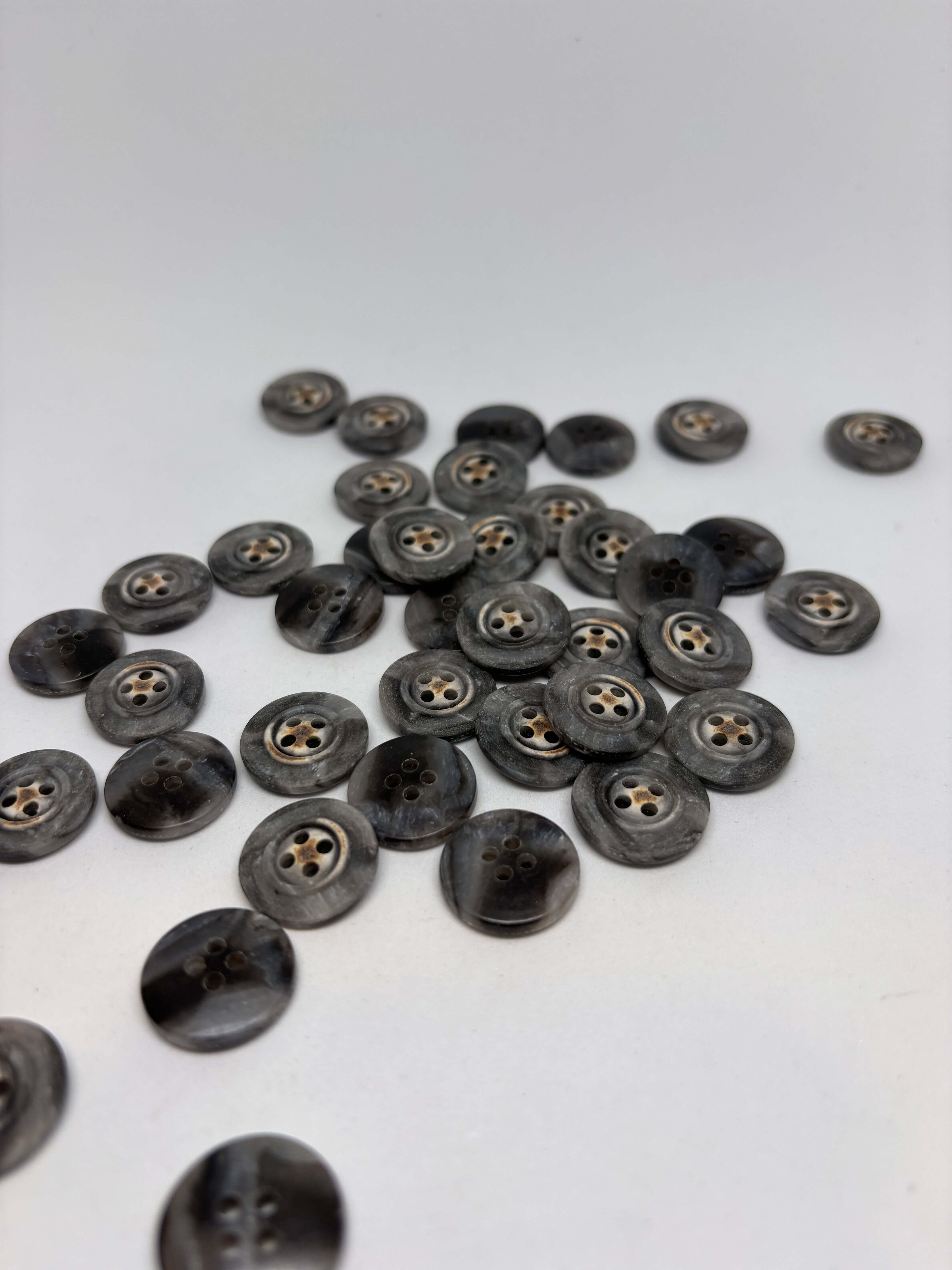 Botón 340MP Gris 4 Agujeros Plano 20mm con textura marmoleada tipo cuerno y detalle central de estrella oxidada. button