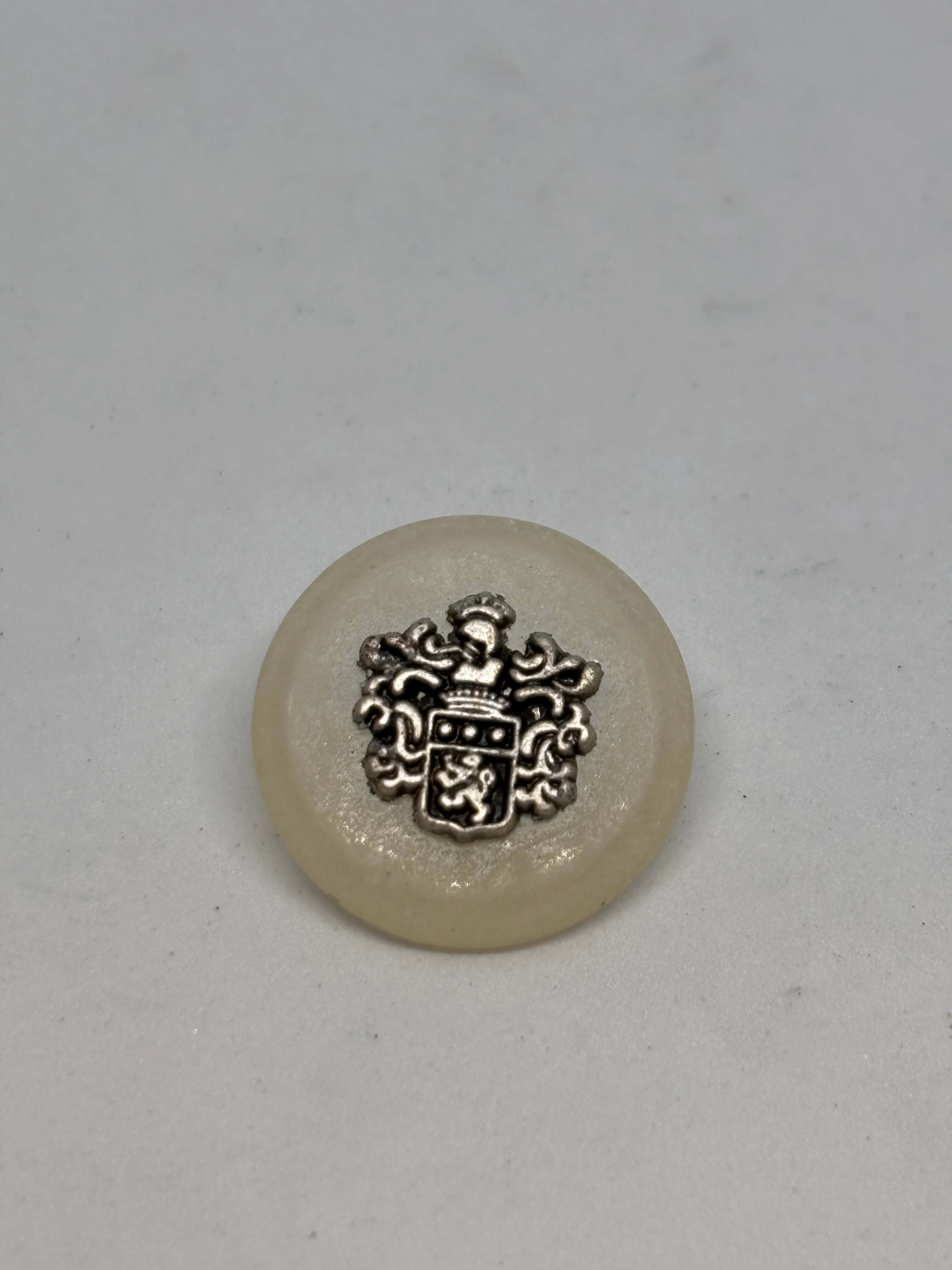 Botón 8400/F3 de vástago ecru 22mm con cresta heráldica, acabado blanco roto brillante, lujo vintage clásico. button