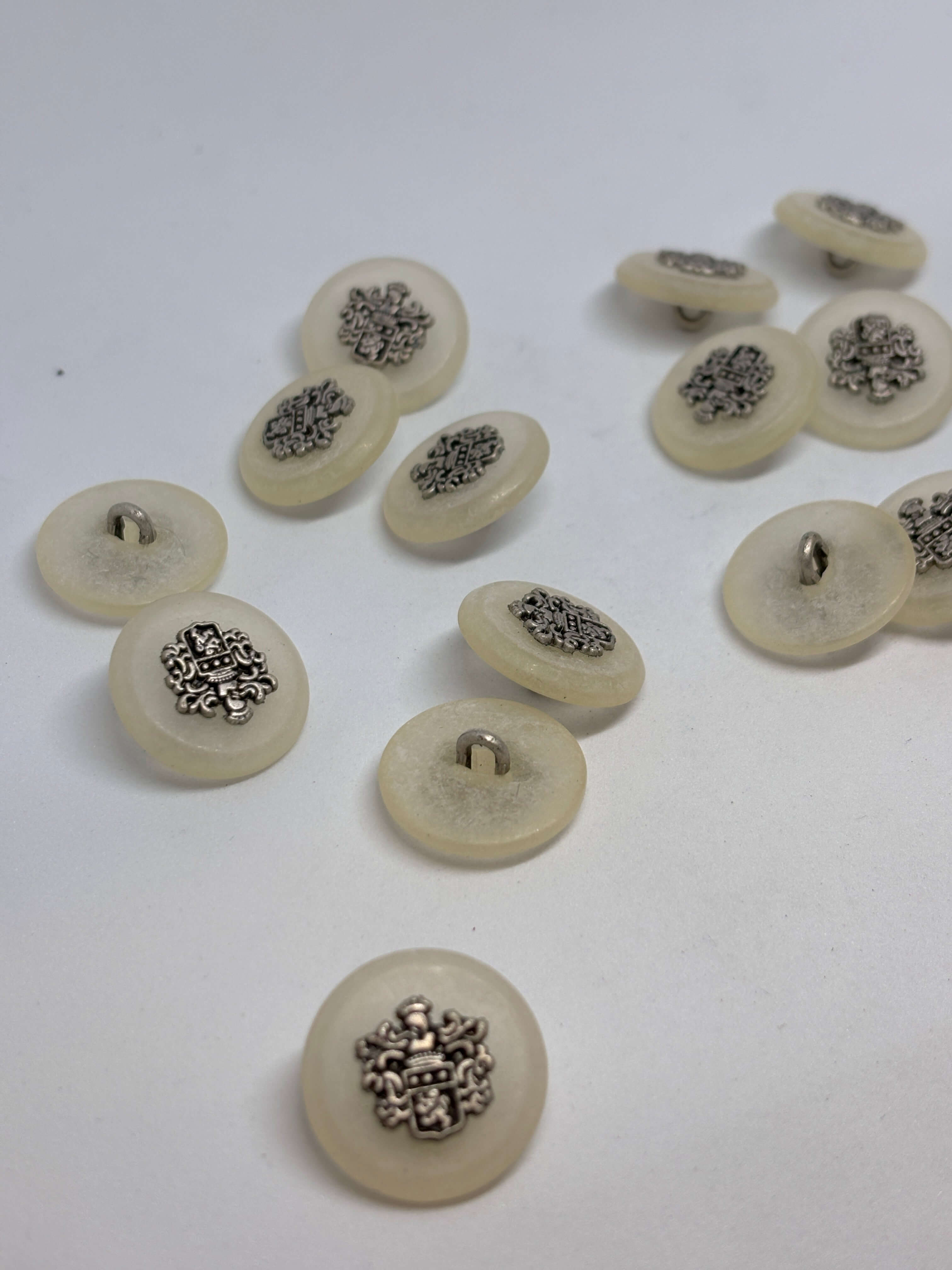 Botón 8400/F3 de vástago ecru 22mm con cresta heráldica, acabado blanco roto brillante, lujo vintage clásico. button