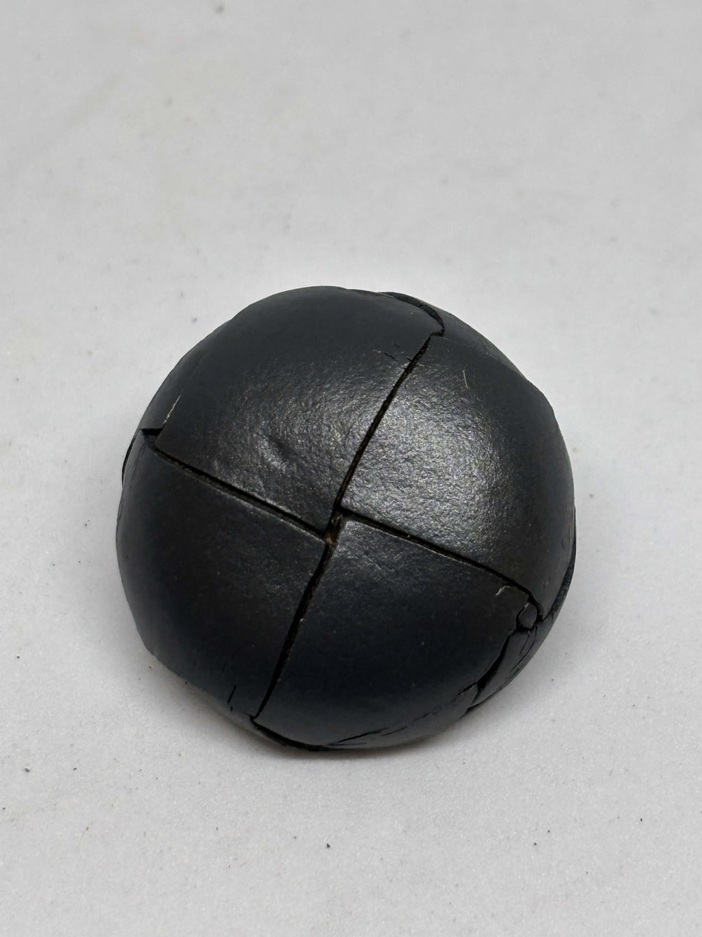 Button B1 Gray genuine leather shank button showcasing a four-section stitched pattern in a domed shape. botón