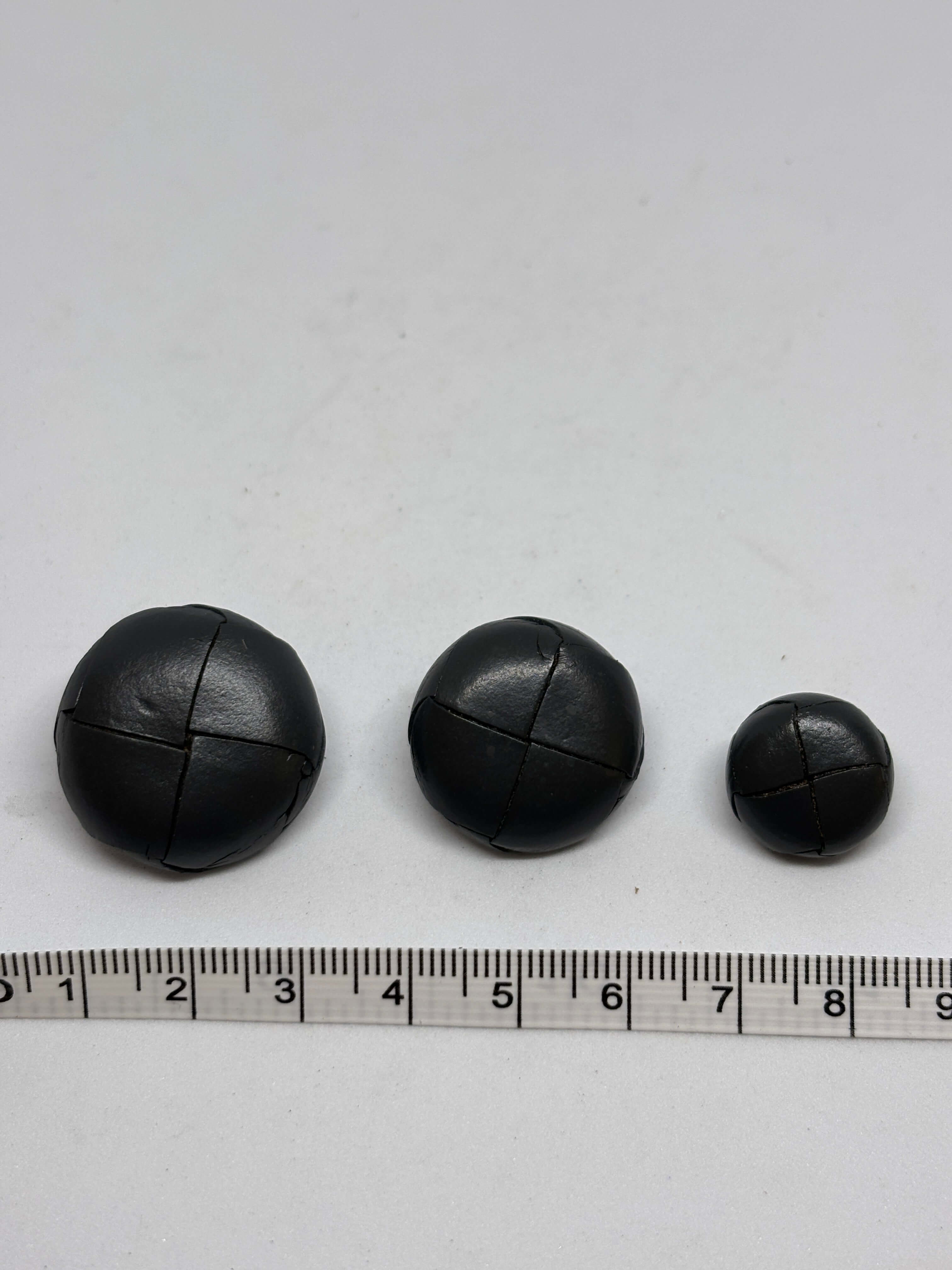 Button B1 Gray genuine leather shank button showcasing a four-section stitched pattern in a domed shape. botón