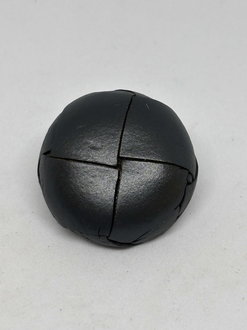 Button B1 Gray genuine leather shank button showcasing a four-section stitched pattern in a domed shape. botón