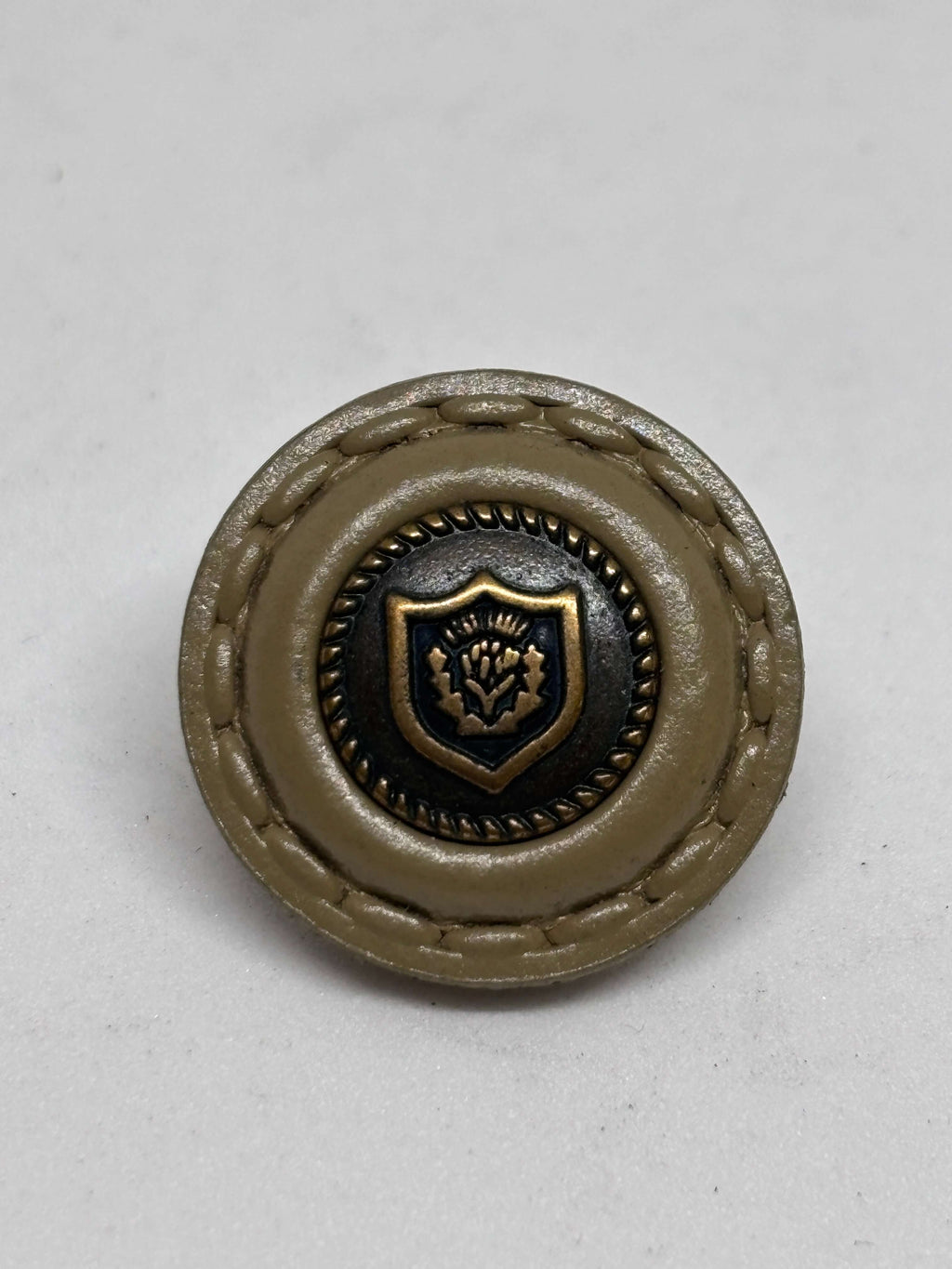 Botón de cuero con diseño en relieve, color beige con detalle dorado, opción elegante para prendas. button