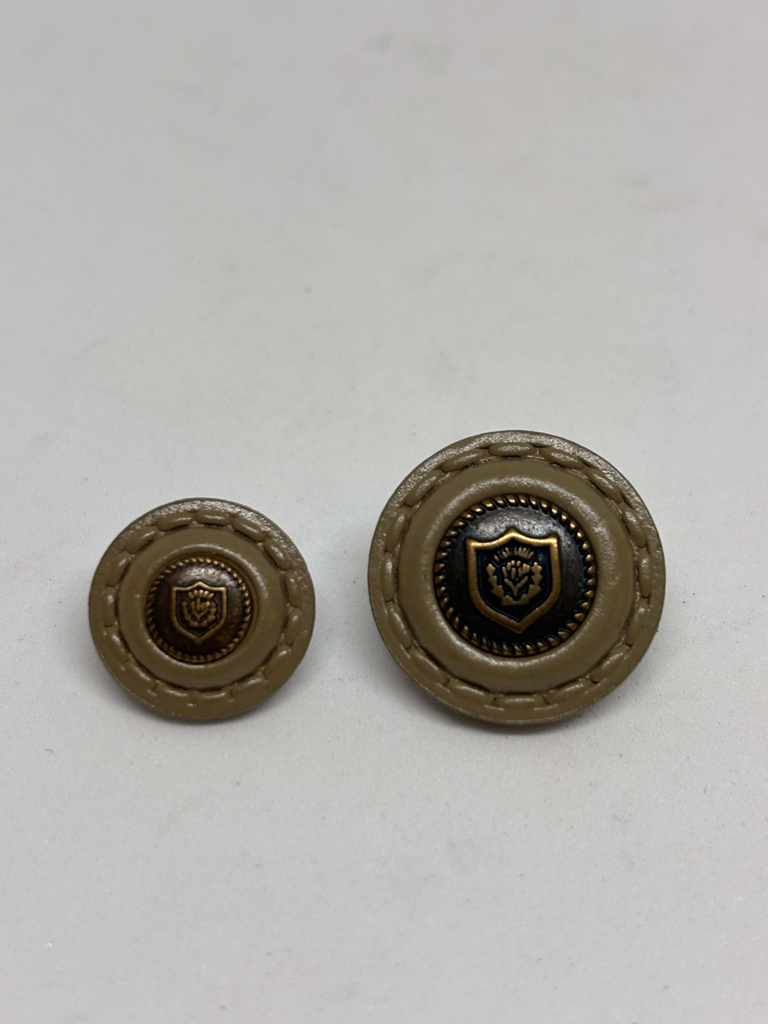 Botón de cuero con diseño en relieve, color beige con detalle dorado, opción elegante para prendas. button