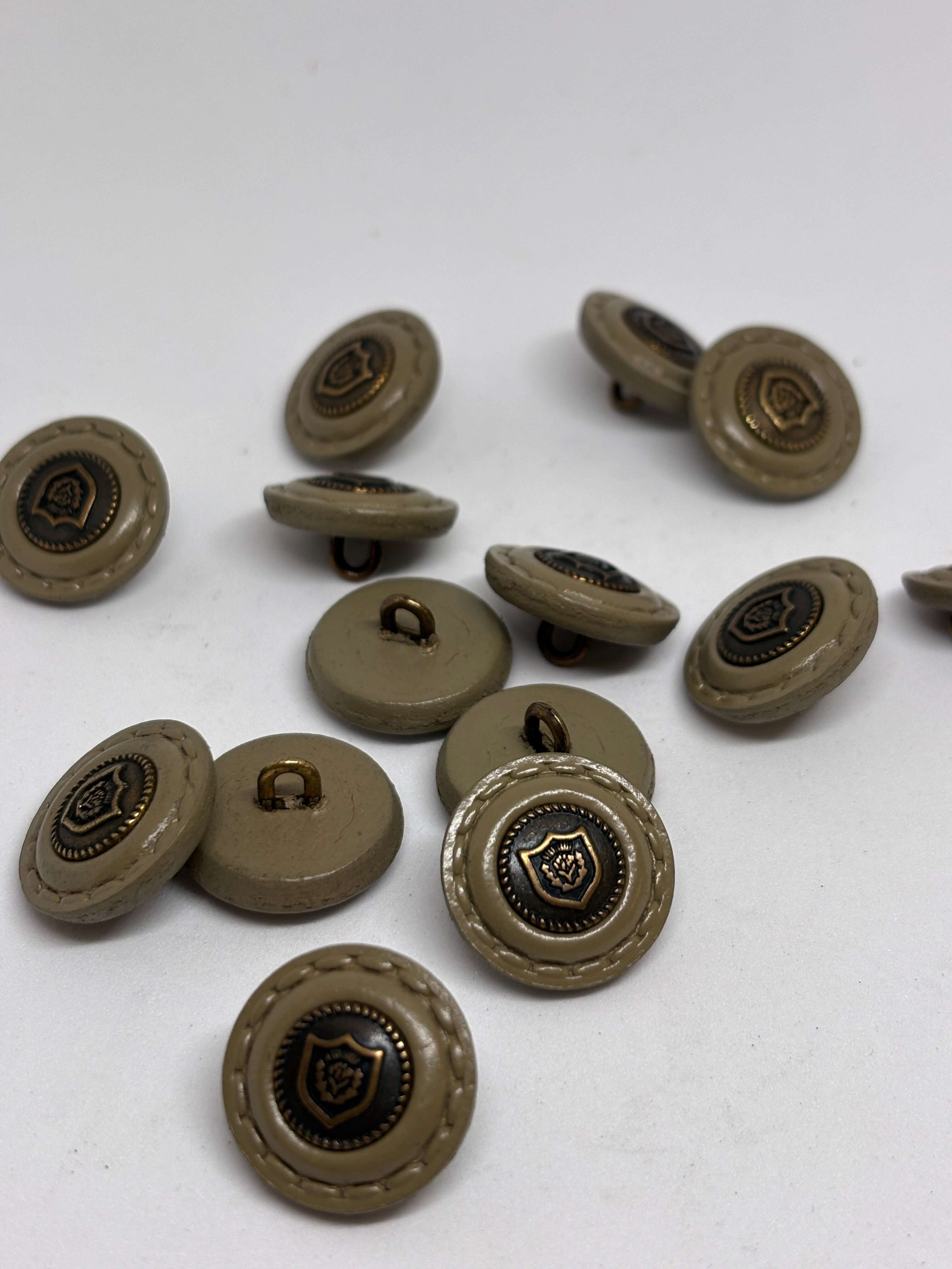 Botón de cuero con diseño en relieve, color beige con detalle dorado, opción elegante para prendas. button