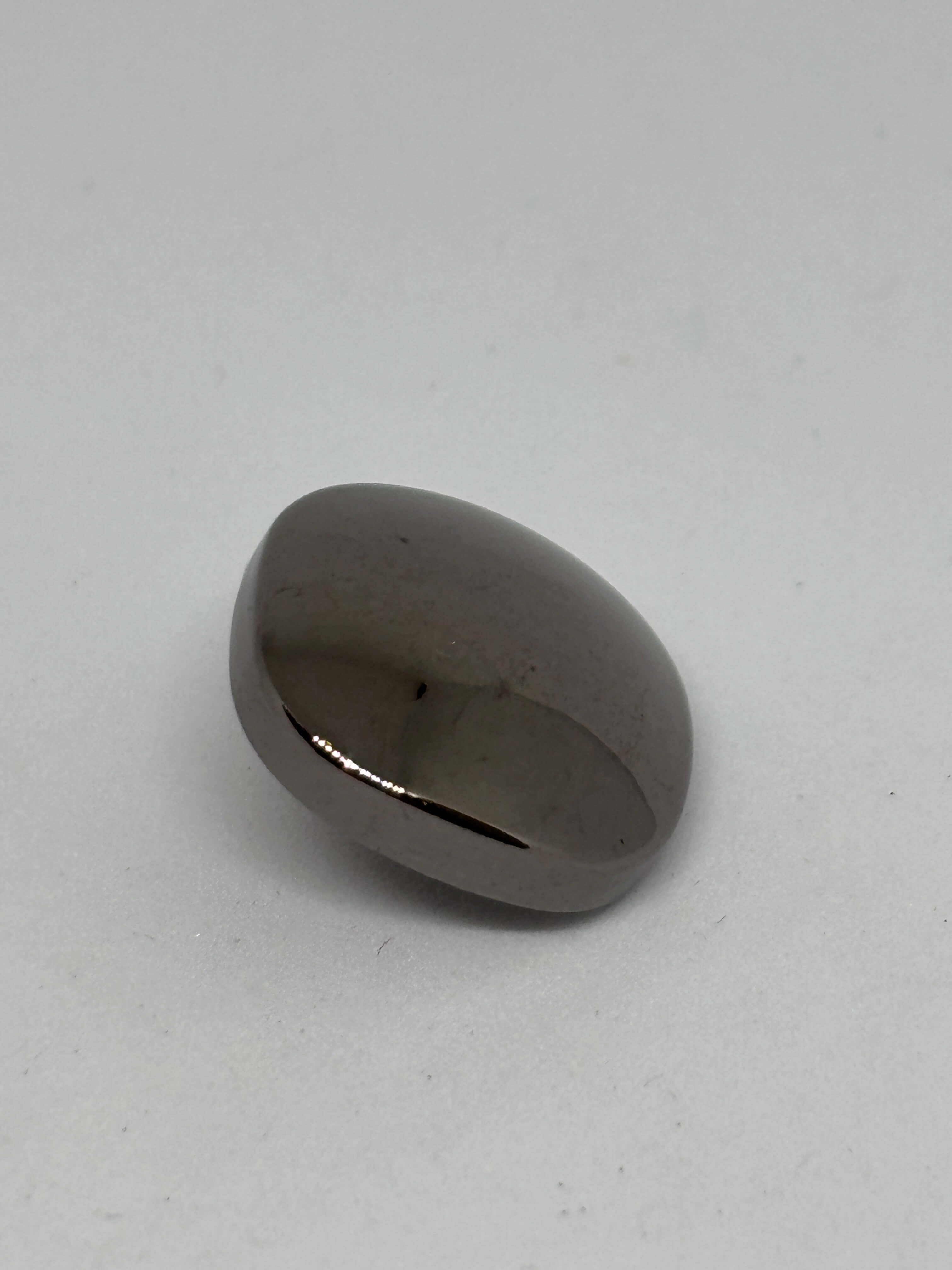 Botón Piedra de forma ovalada con acabado brillante y color gris oscuro sobre fondo claro. button