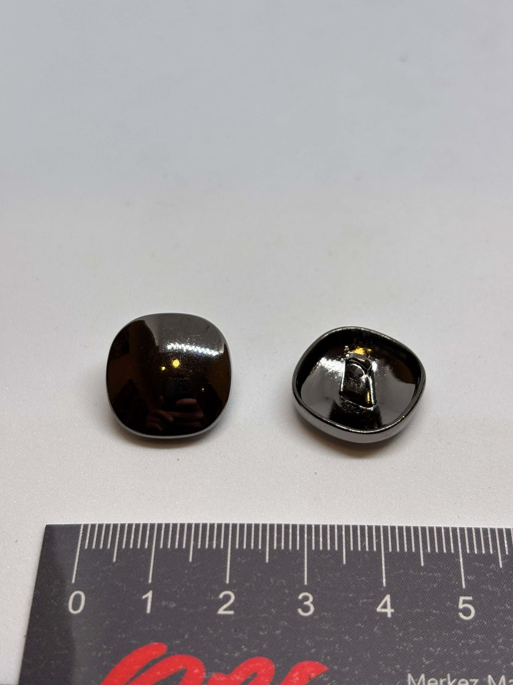 Botón Piedra de forma ovalada con acabado brillante y color gris oscuro sobre fondo claro. button