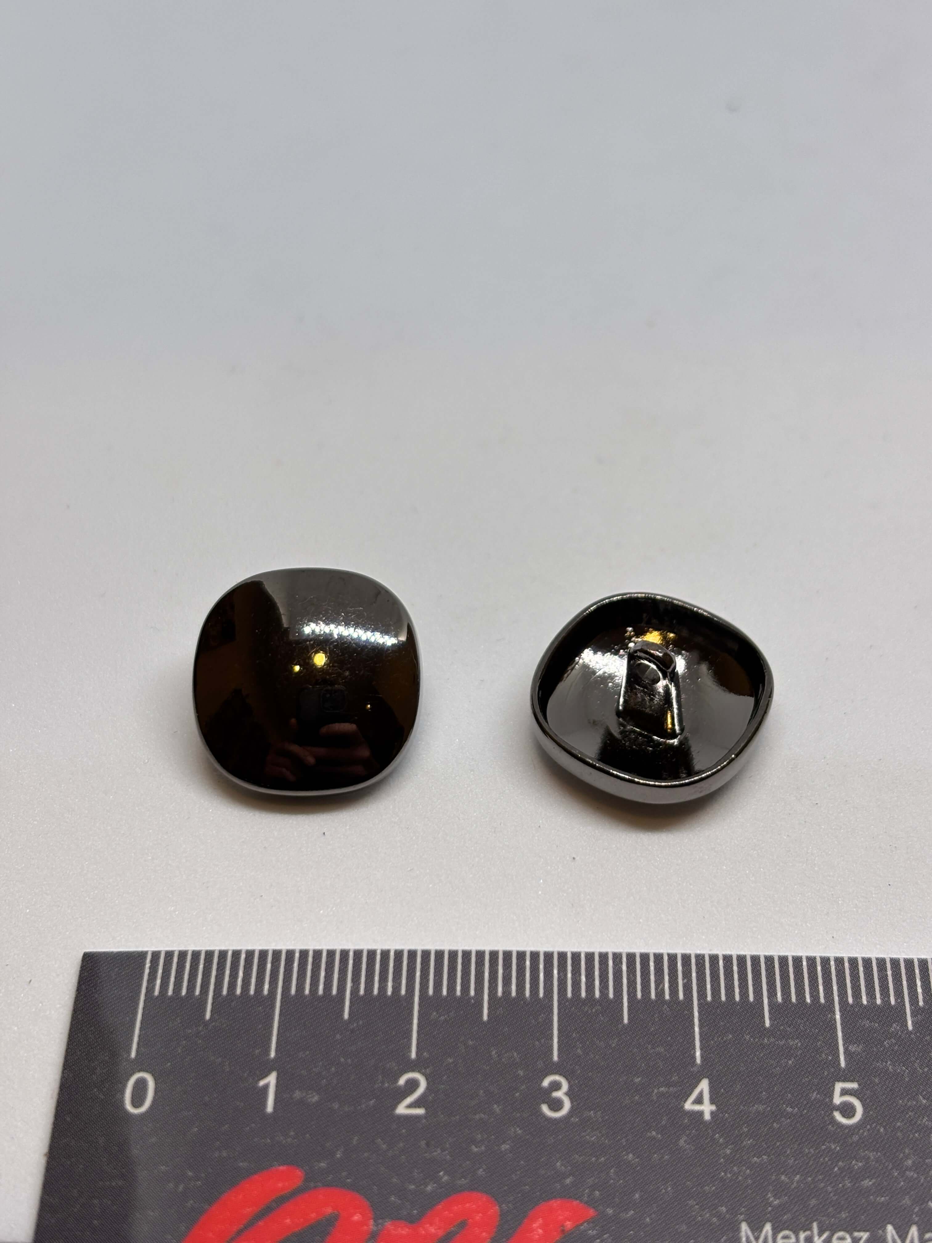 Botón Piedra de forma ovalada con acabado brillante y color gris oscuro sobre fondo claro. button