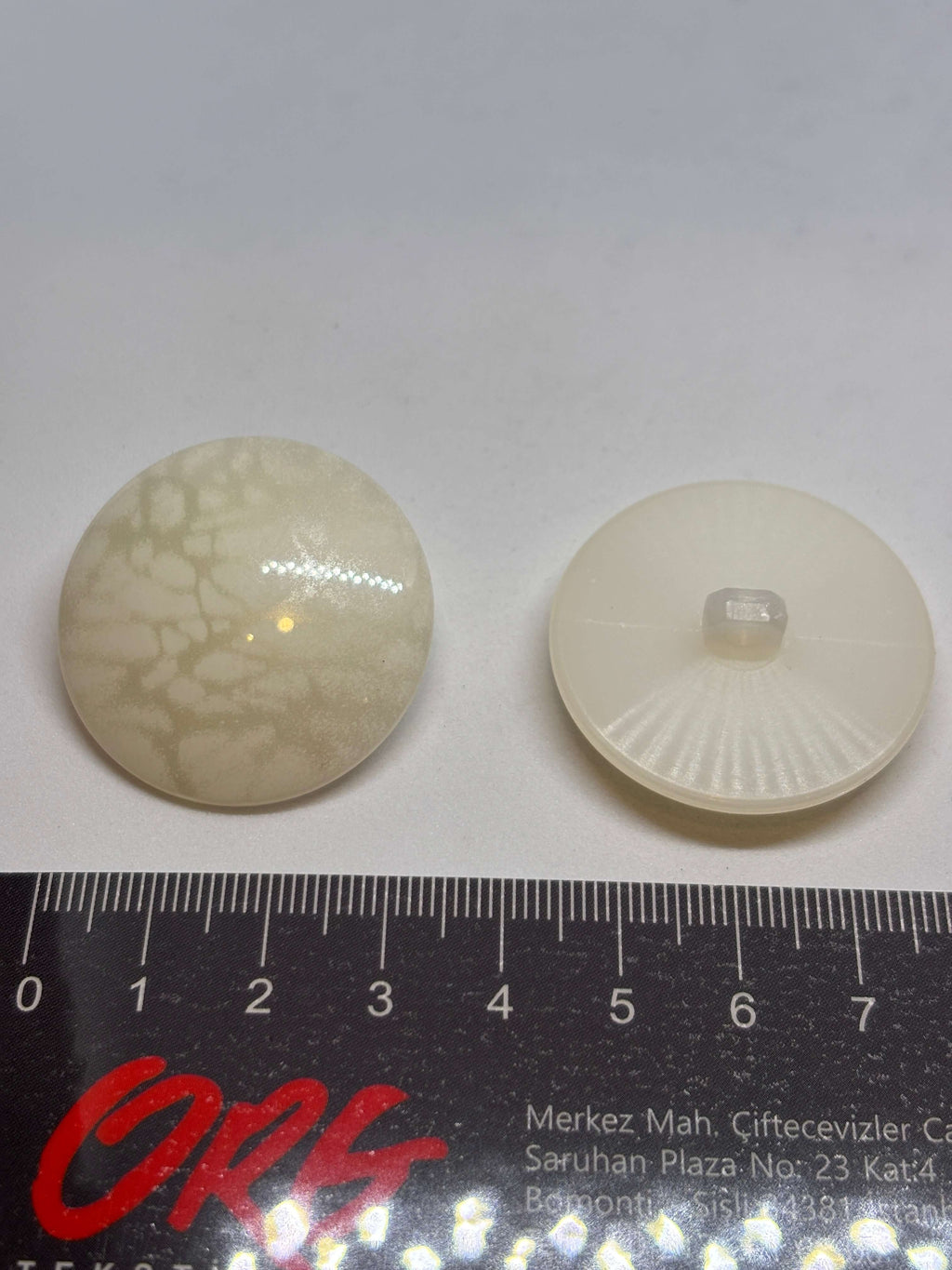 Botón B5979 de vástago de poliéster ecru 34mm con acabado brillante y veteado sutil tipo mármol. button