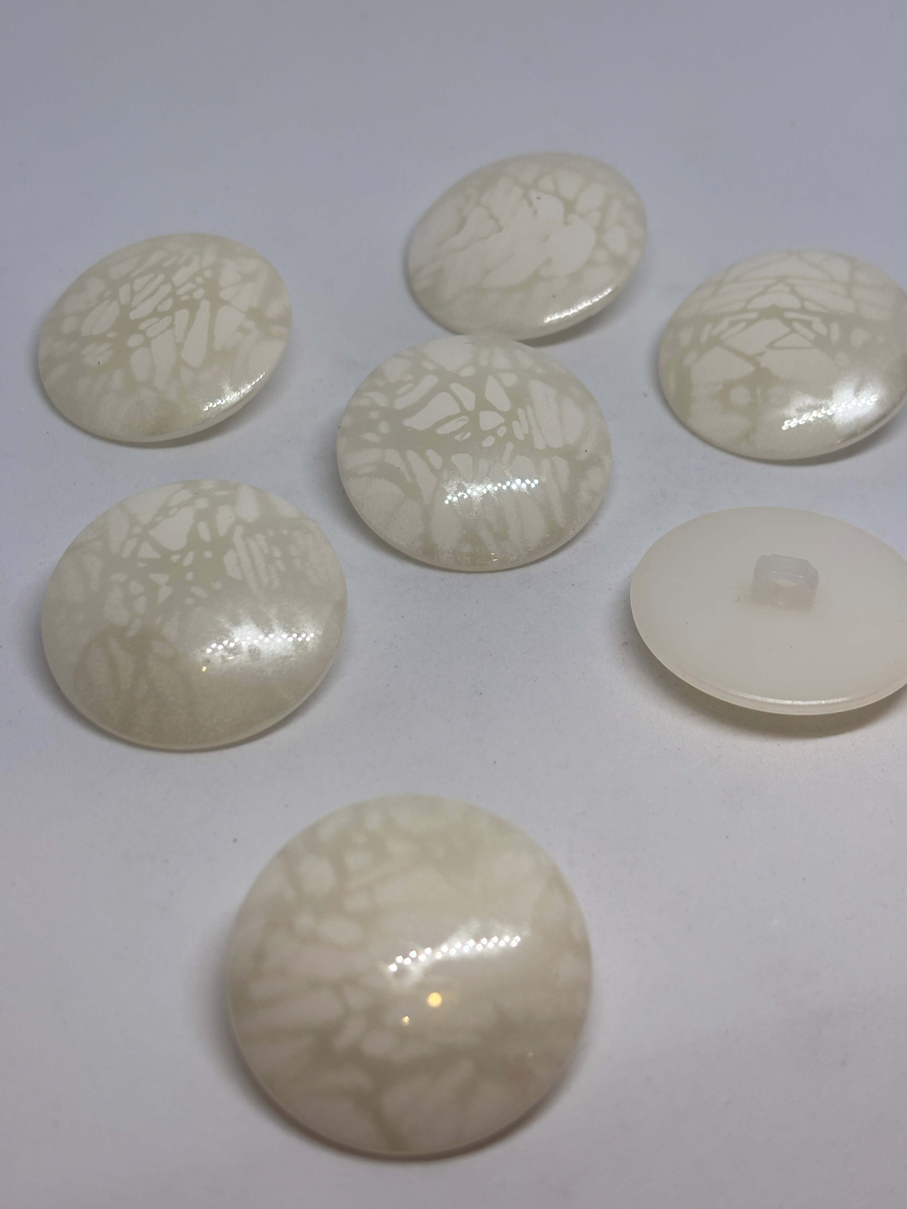 Botón B5979 de vástago de poliéster ecru 34mm con acabado brillante y veteado sutil tipo mármol. button