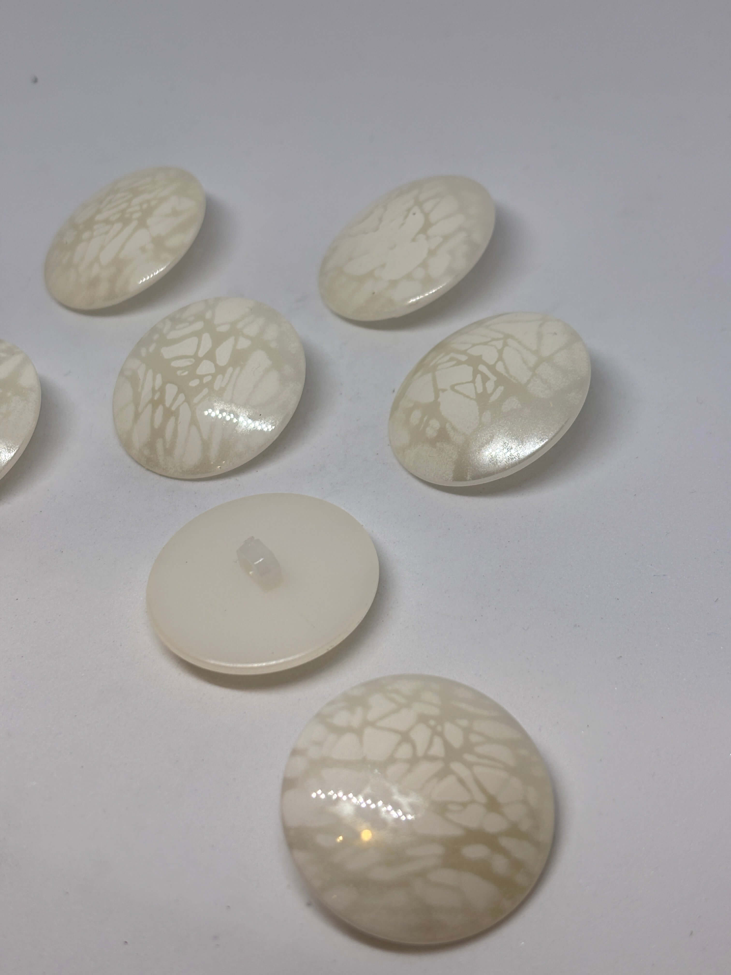 Botón B5979 de vástago de poliéster ecru 34mm con acabado brillante y veteado sutil tipo mármol. button