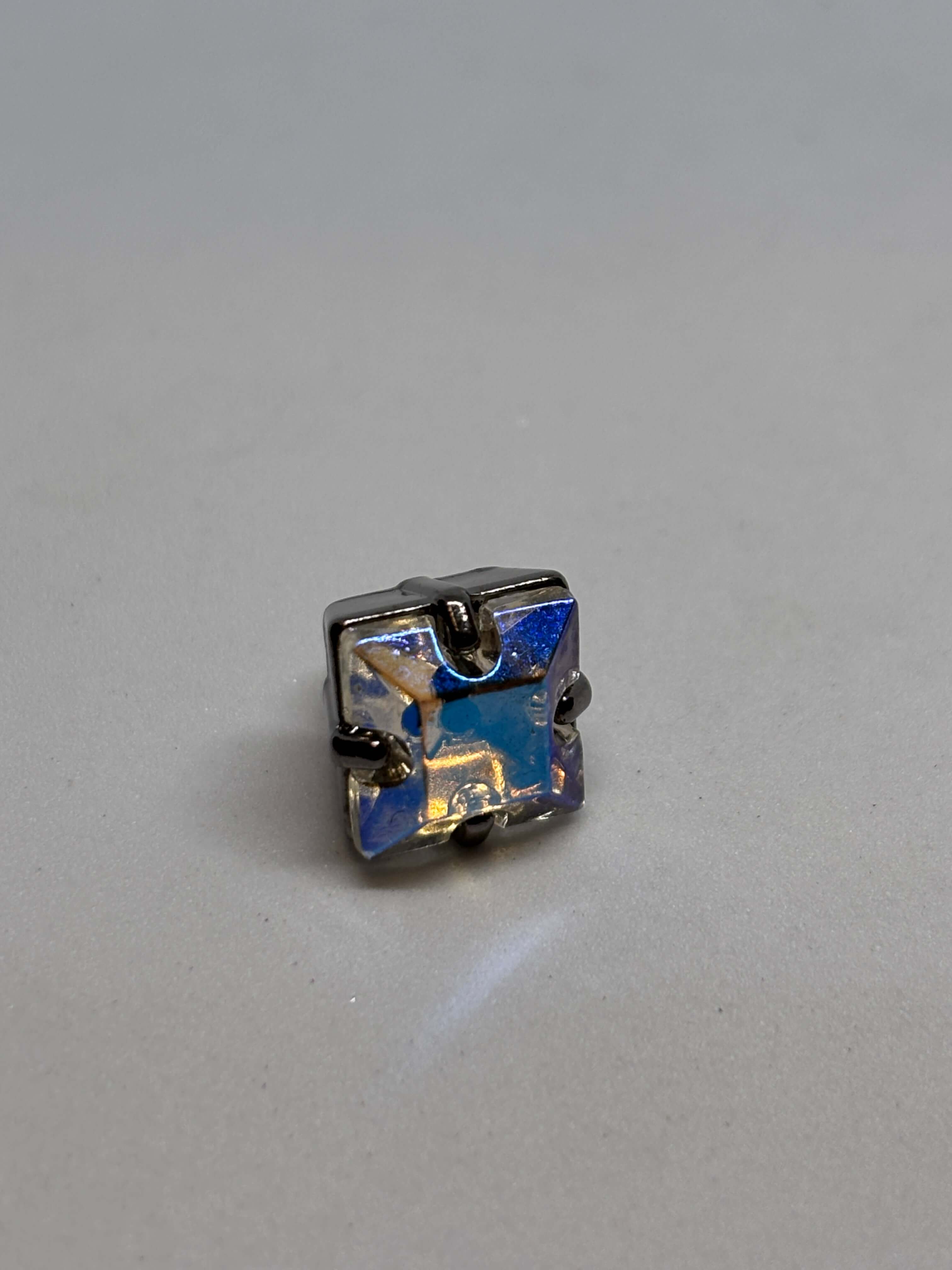 Botón cuadrado con acabado brillante en tonos azules y plateados, ideal para decoración elegante y sofisticada. button