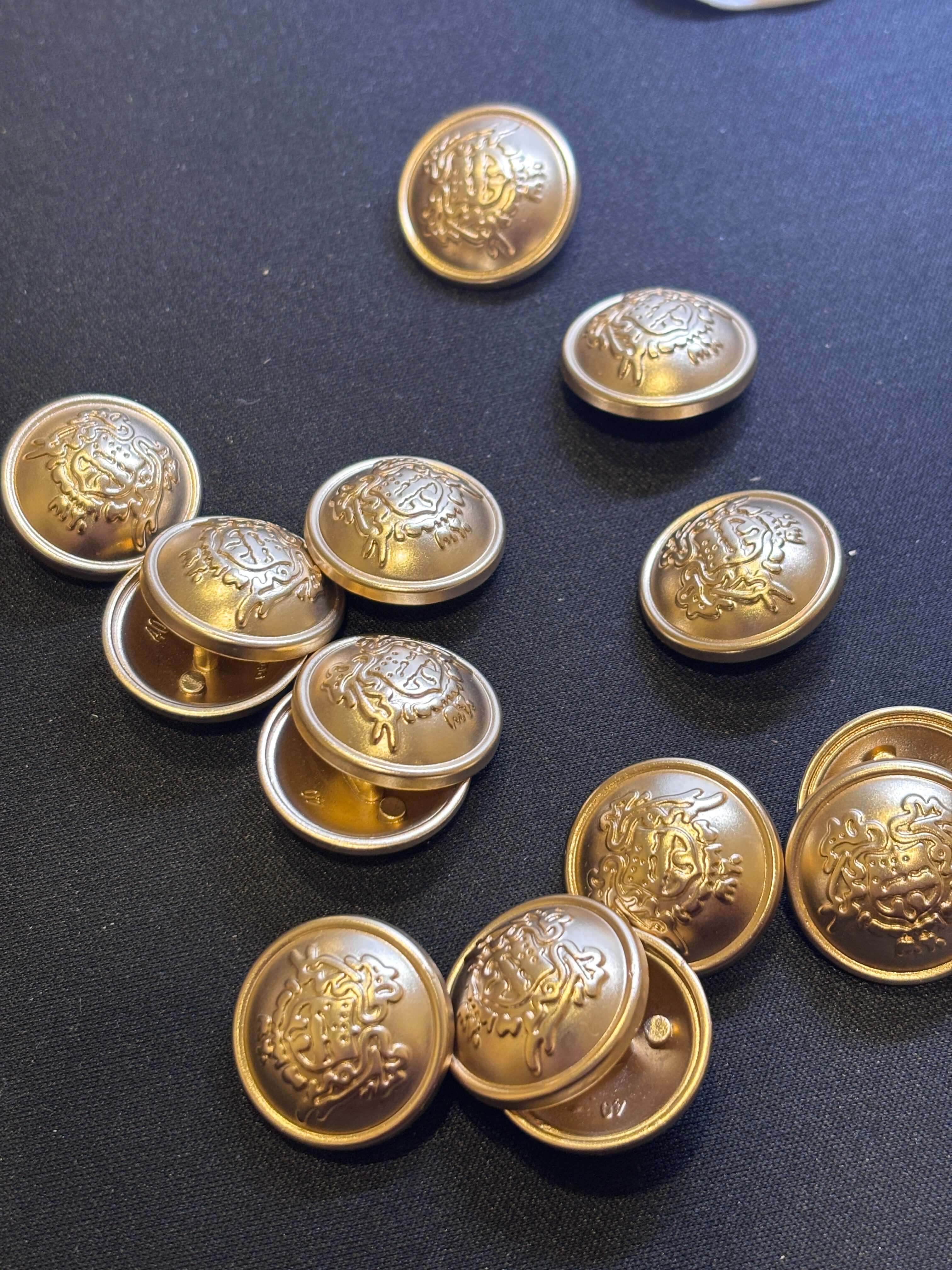 Botón M6054 de vástago en oro con diseño de cresta heráldica, ideal para prendas elegantes, 25mm. button