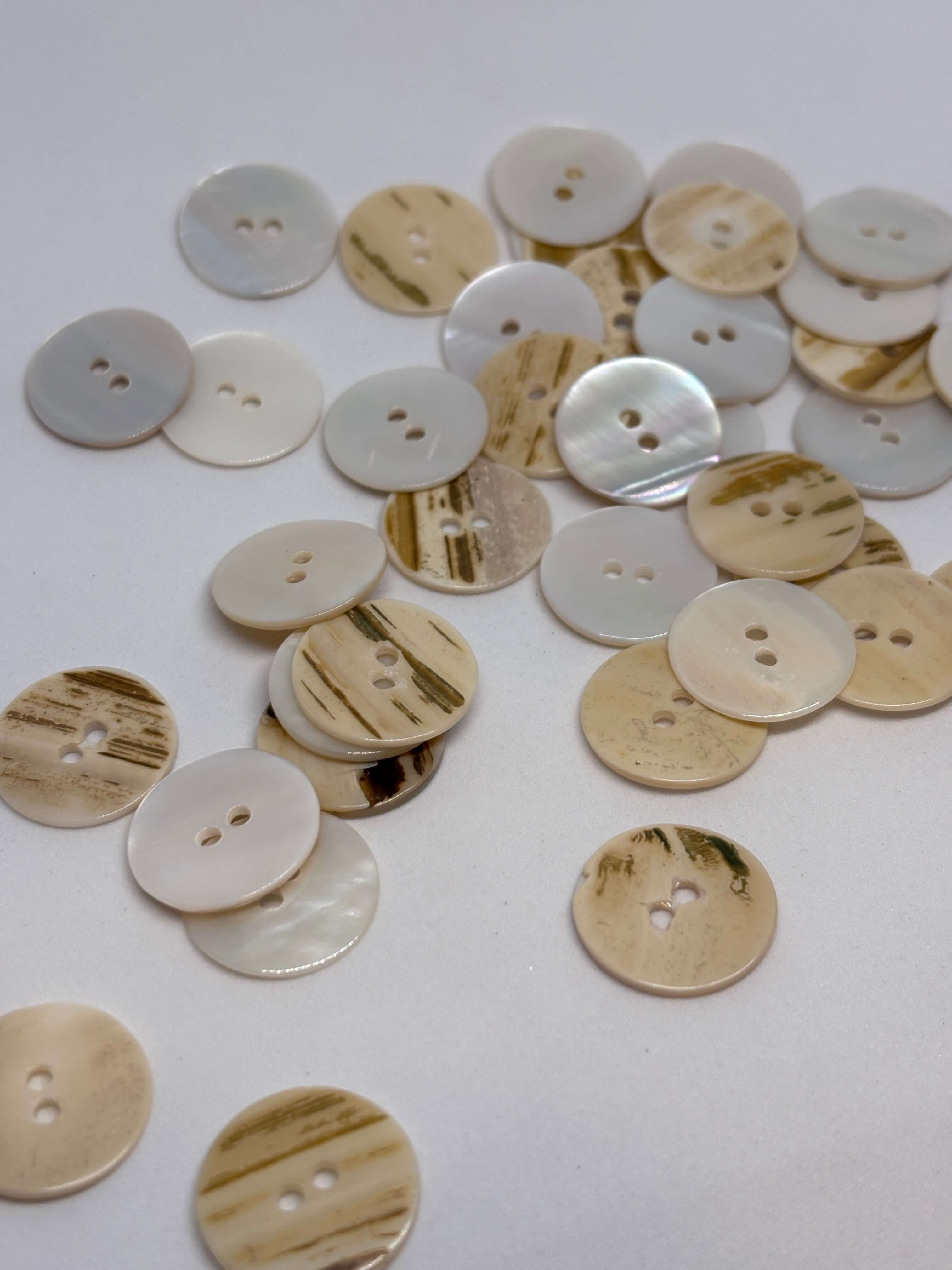 Botón T35/2H Nácar Natural 2 Agujeros 18mm en color marfil-crema con textura rayada y brillo perlado. button