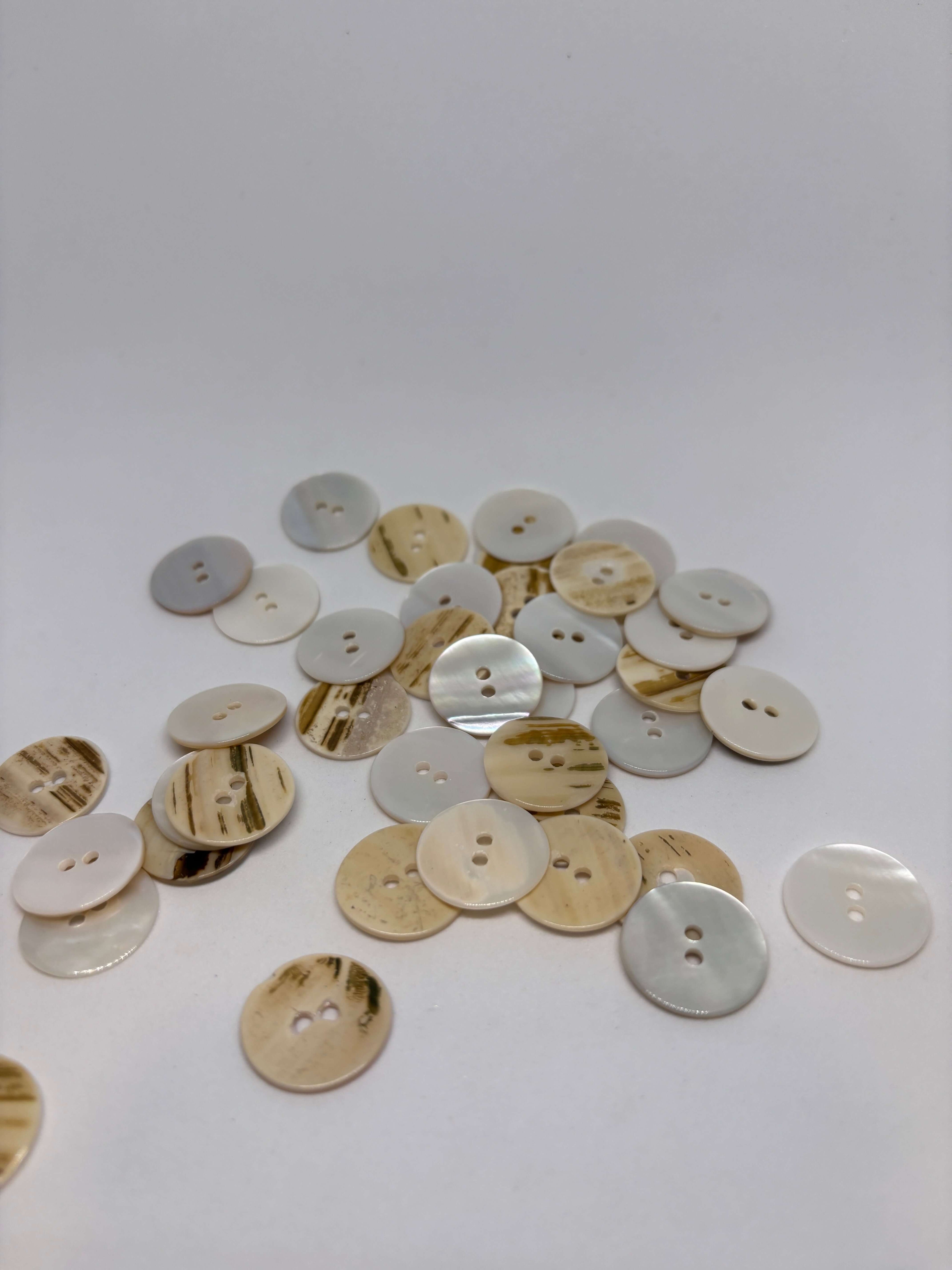 Botón T35/2H Nácar Natural 2 Agujeros 18mm en color marfil-crema con textura rayada y brillo perlado. button