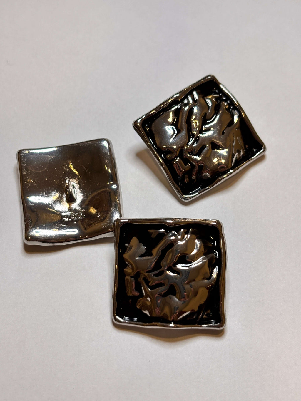 Shiny metal buttons in a square shape, showcasing a 32mm (50") shank button design. botón