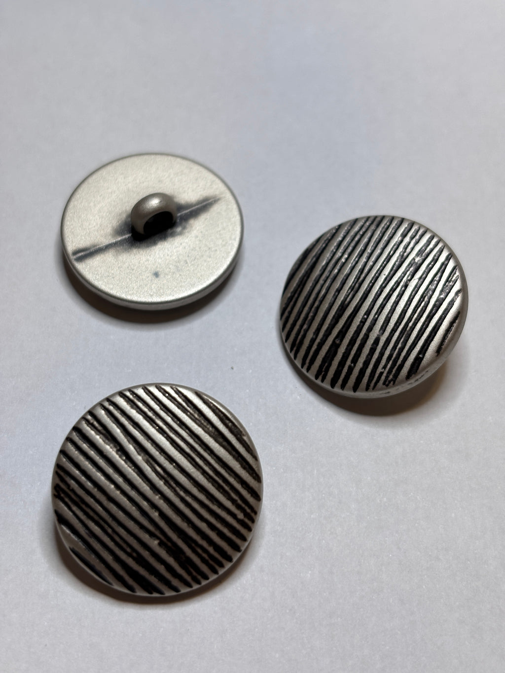 Button B7831 - 18mm (28"), 25mm (40") polyester shank button shown from both sides. boton