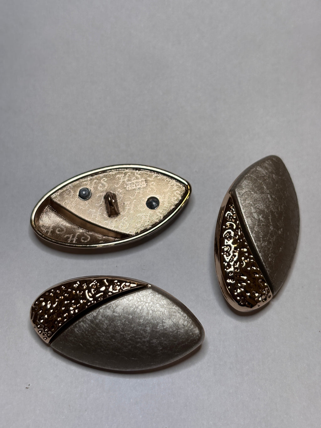 Button F958 - 38mm (60") Shank button showcased in metallic design, including decorative elements. boton