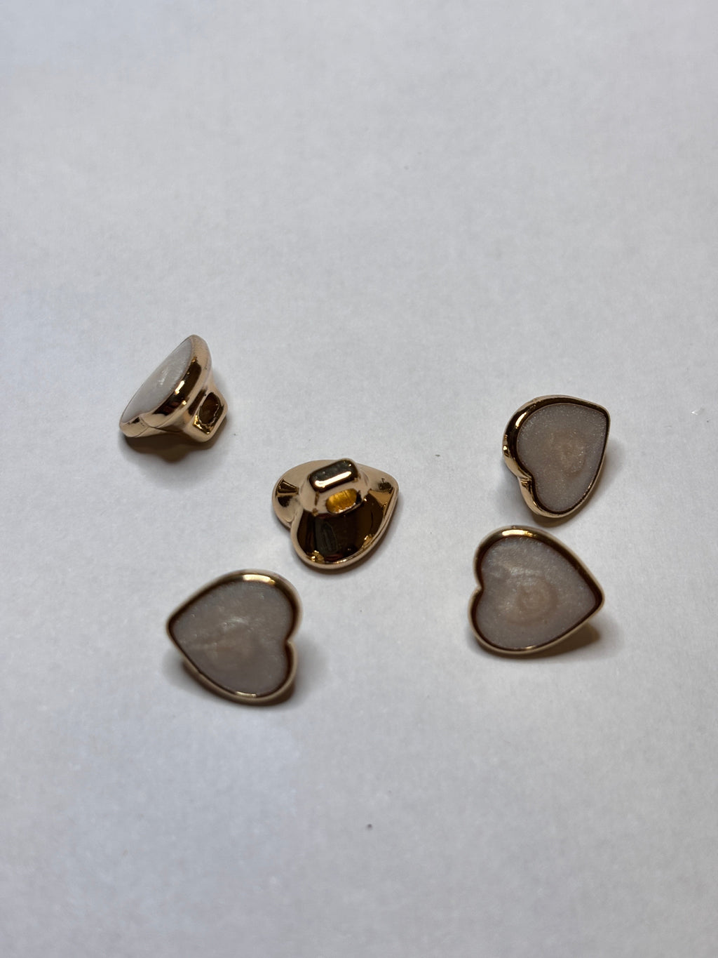 Heart-shaped metal buttons featuring a gold finish, perfect for sewing and craft projects, showcasing the elegance of a button. boton