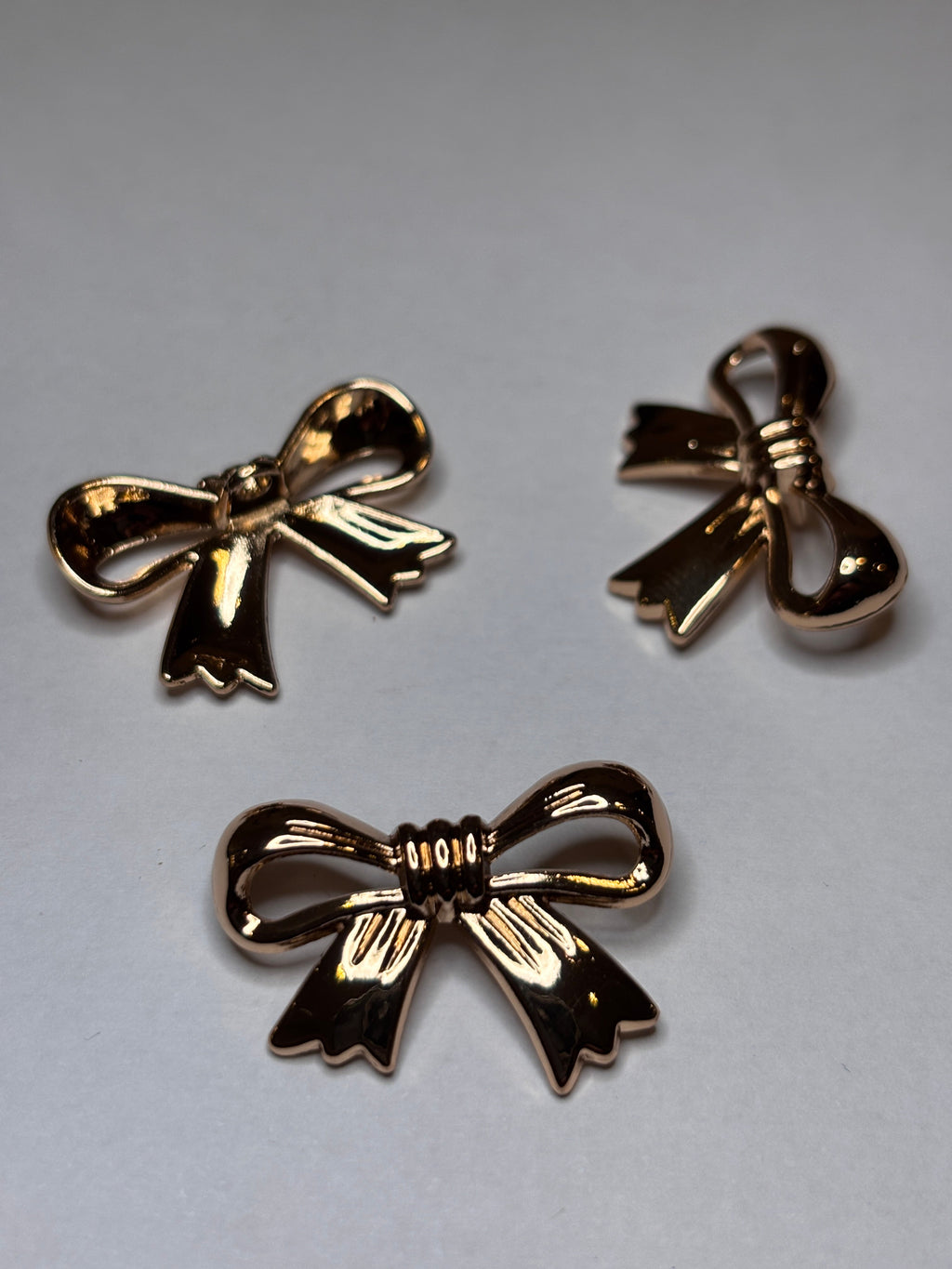 Decorative gold shank buttons shaped like bows, perfect for crafting and embellishing. boton