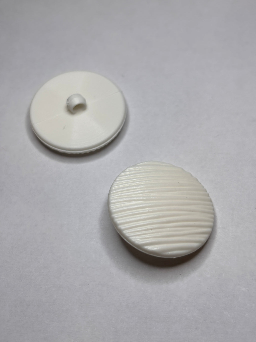 Button B7831 - 18mm (28"), 25mm (40") polyester shank button shown from both sides. boton