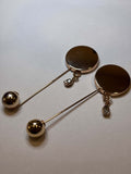 Elegant gold brooch featuring a round design with dangling elements and sparkling details. broche
