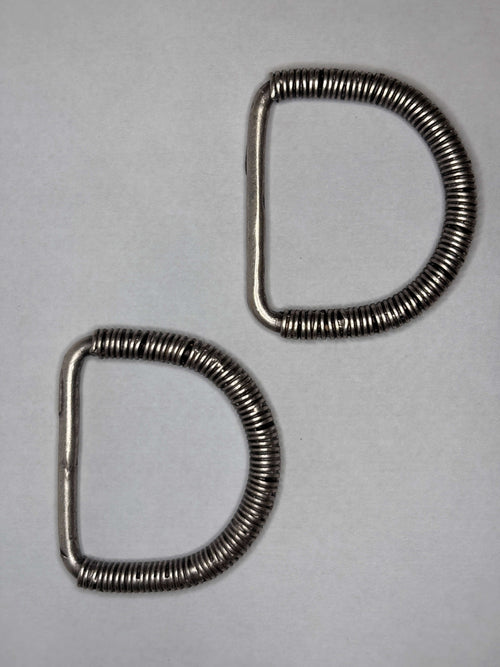 Two metal Buckle 17673 pieces displayed on a grey background, showcasing their unique shape and design. hebilla