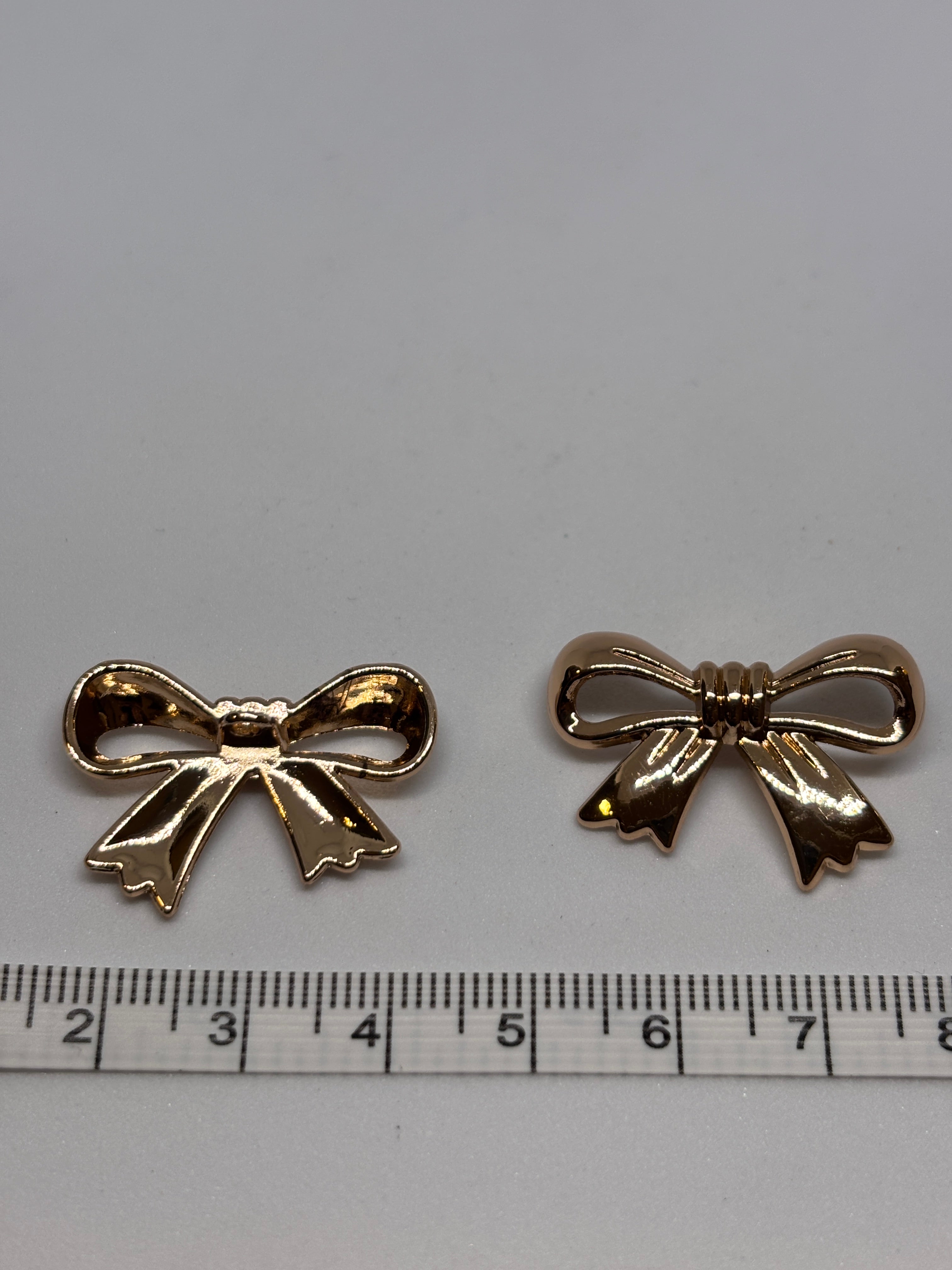 Decorative gold shank buttons shaped like bows, perfect for crafting and embellishing. boton