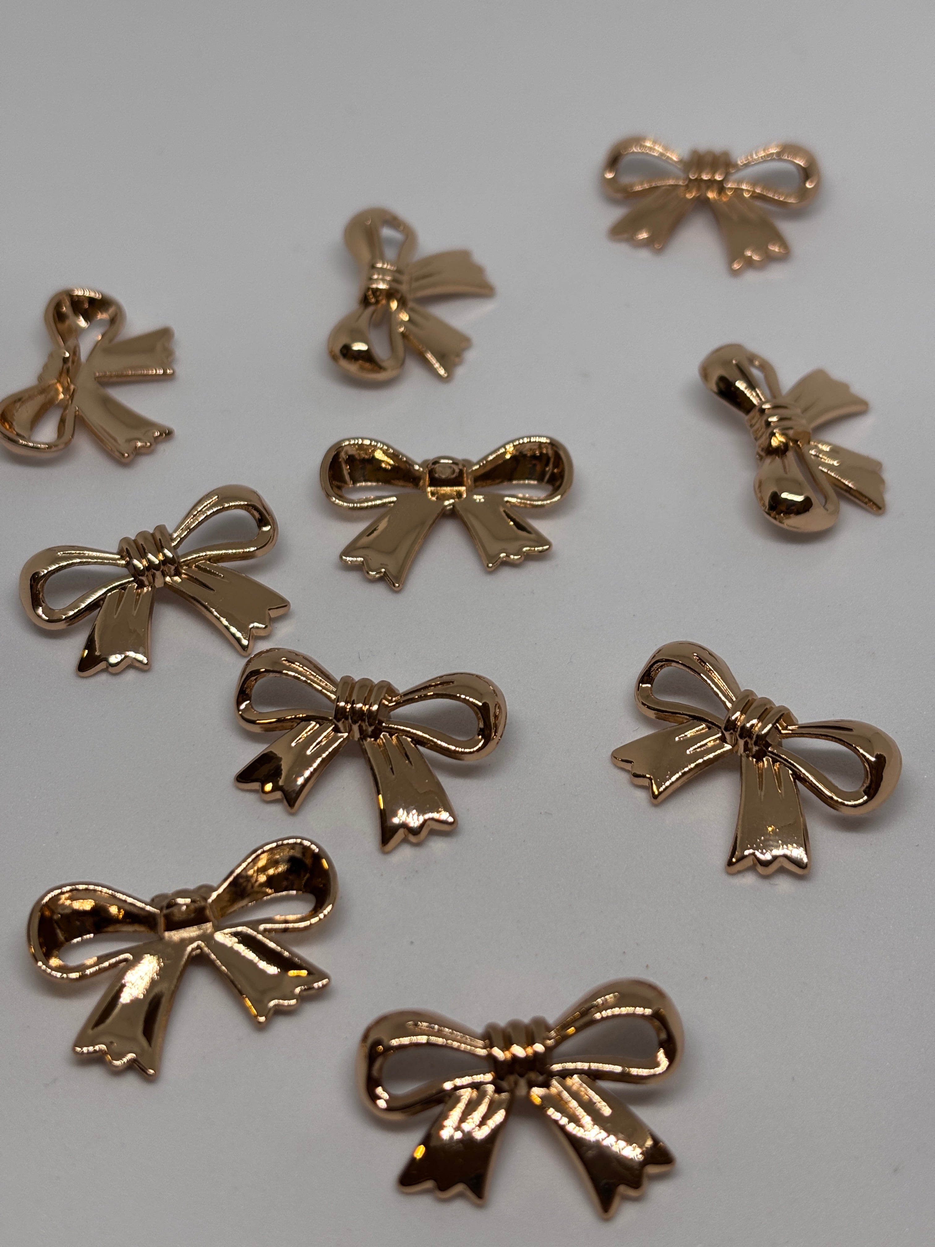 Decorative gold shank buttons shaped like bows, perfect for crafting and embellishing. boton