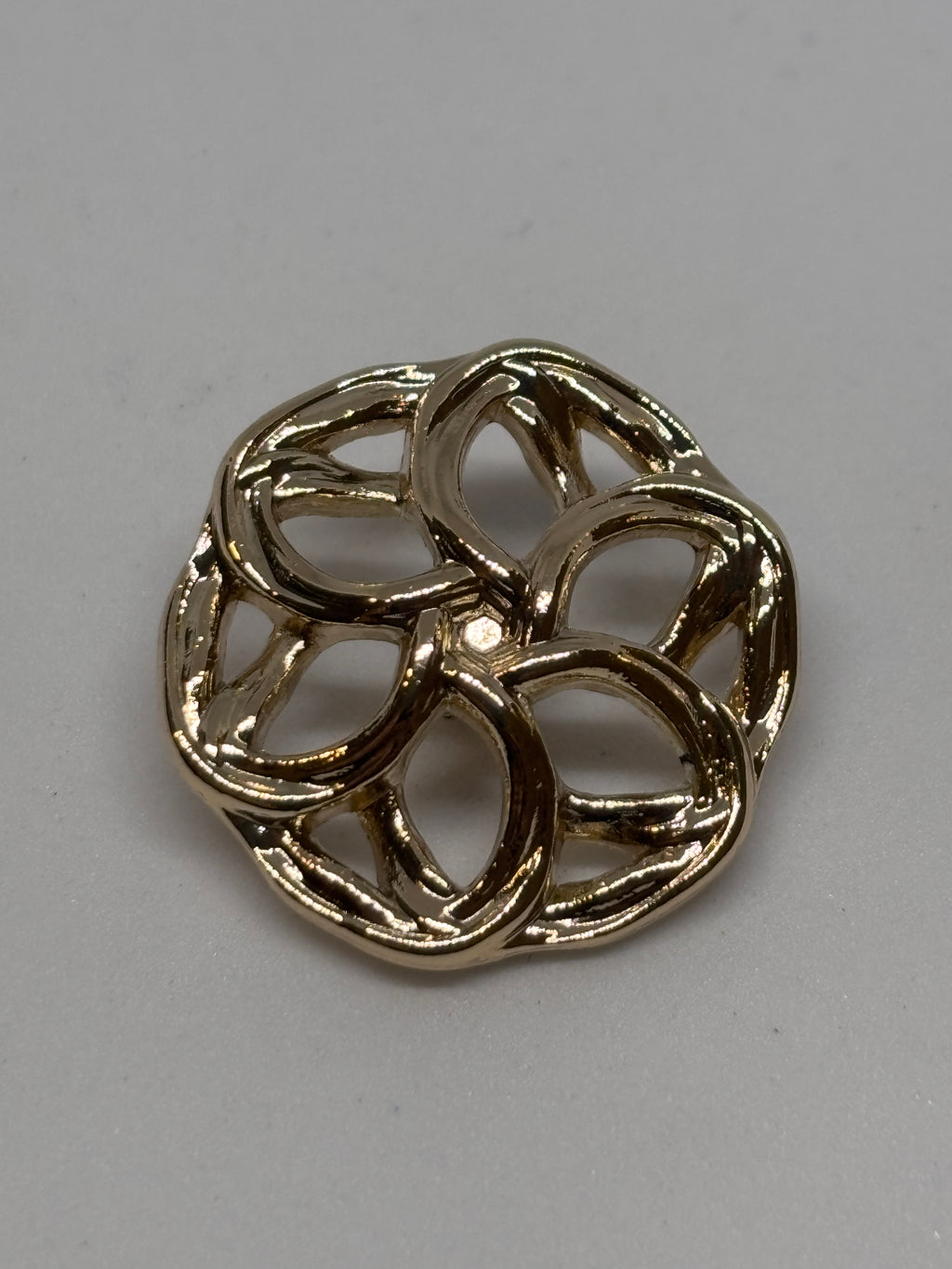 Three decorative metal buttons in a floral design, showcasing their intricate detailing and shine. boton