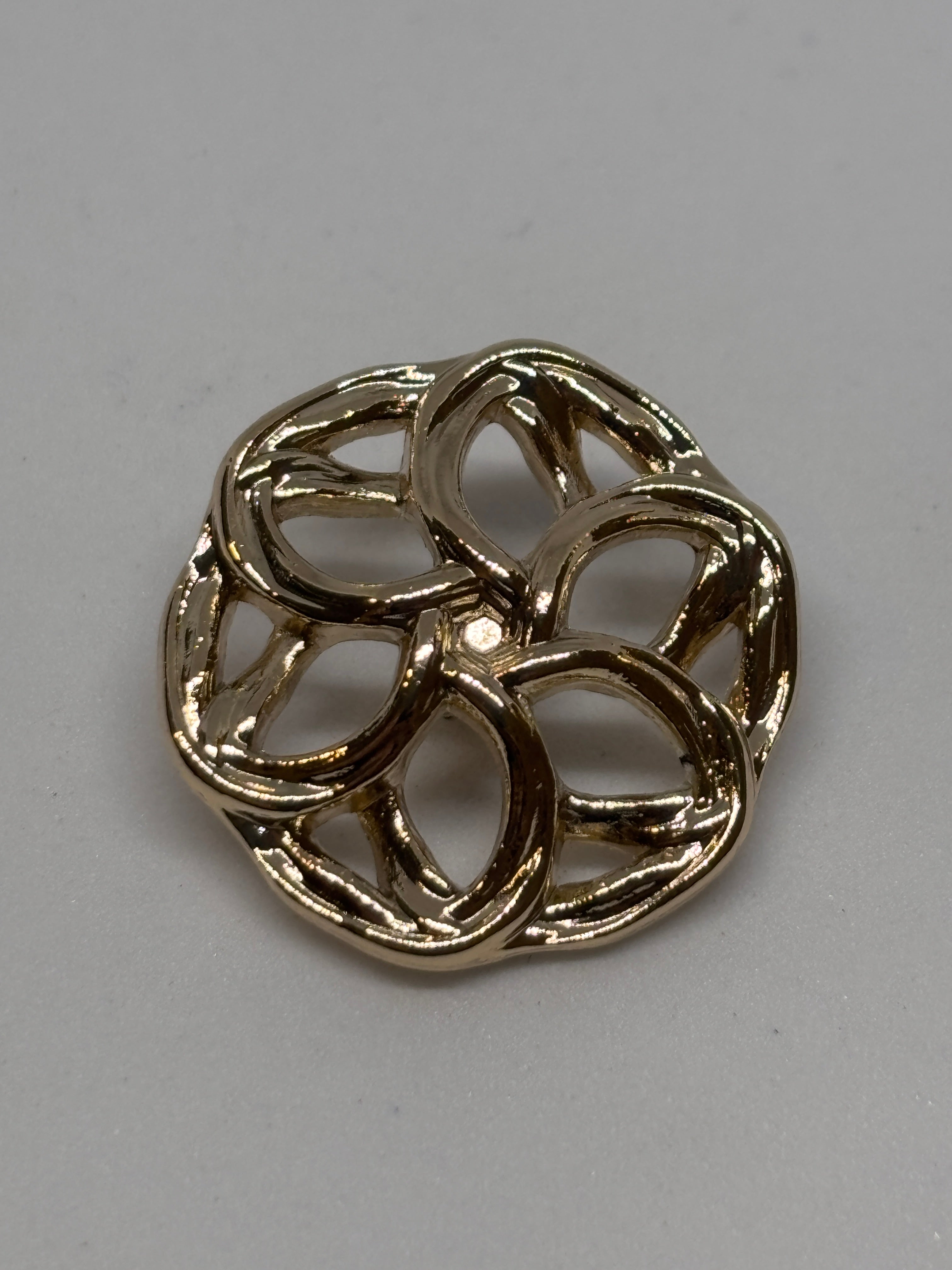 Three decorative metal buttons in a floral design, showcasing their intricate detailing and shine. boton