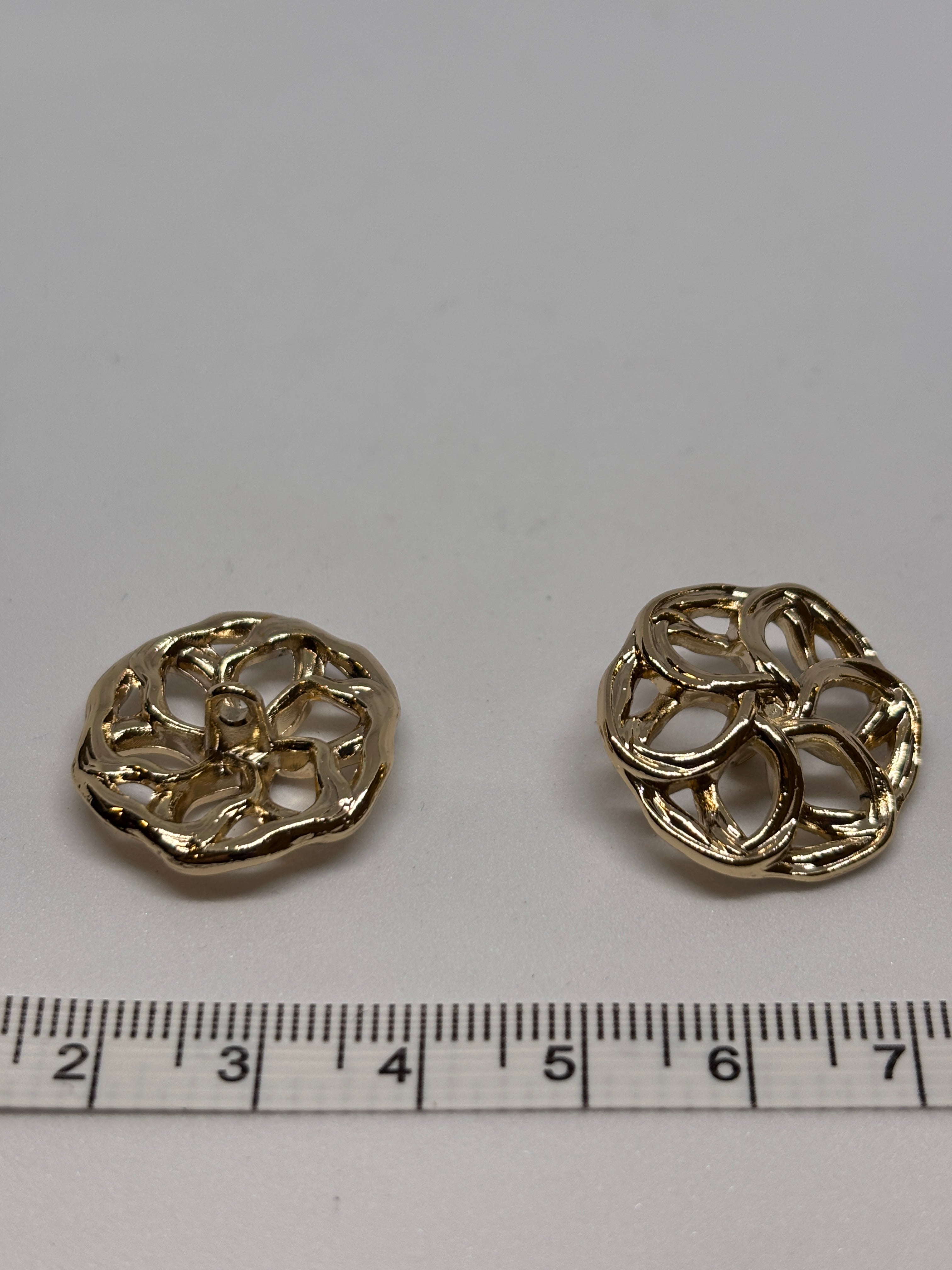 Three decorative metal buttons in a floral design, showcasing their intricate detailing and shine. boton