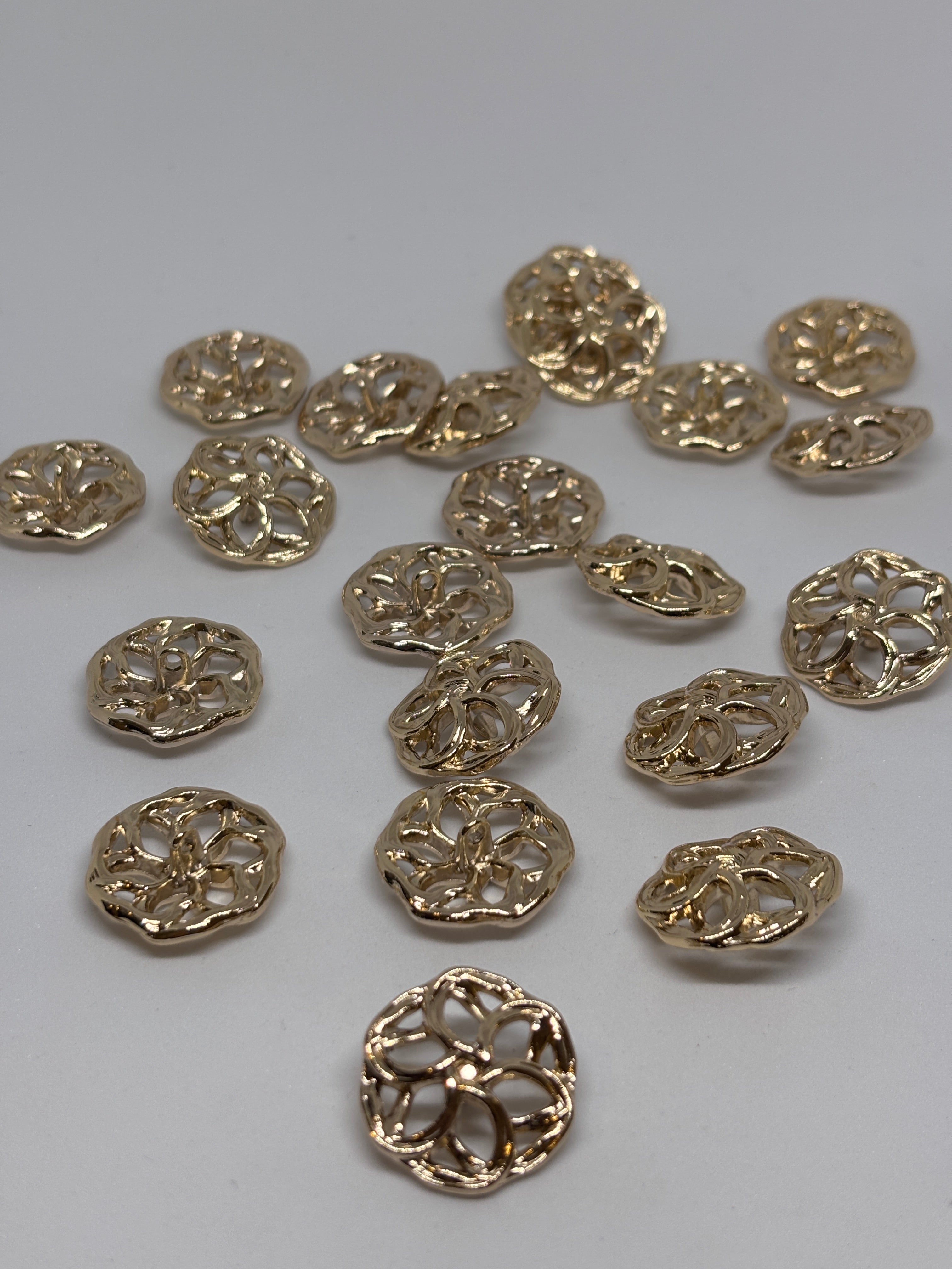 Three decorative metal buttons in a floral design, showcasing their intricate detailing and shine. boton