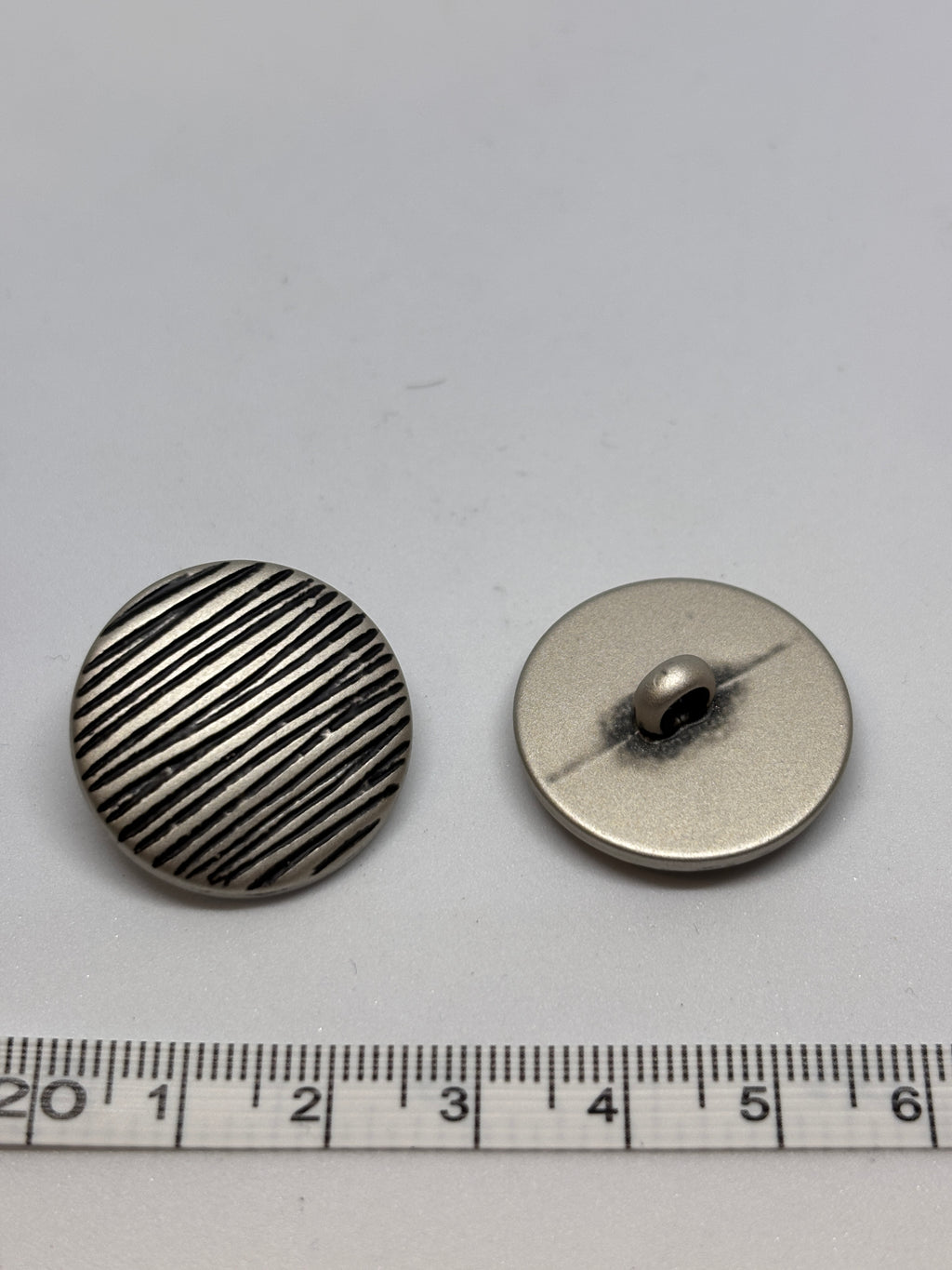 Button B7831 - 18mm (28"), 25mm (40") polyester shank button shown from both sides. boton