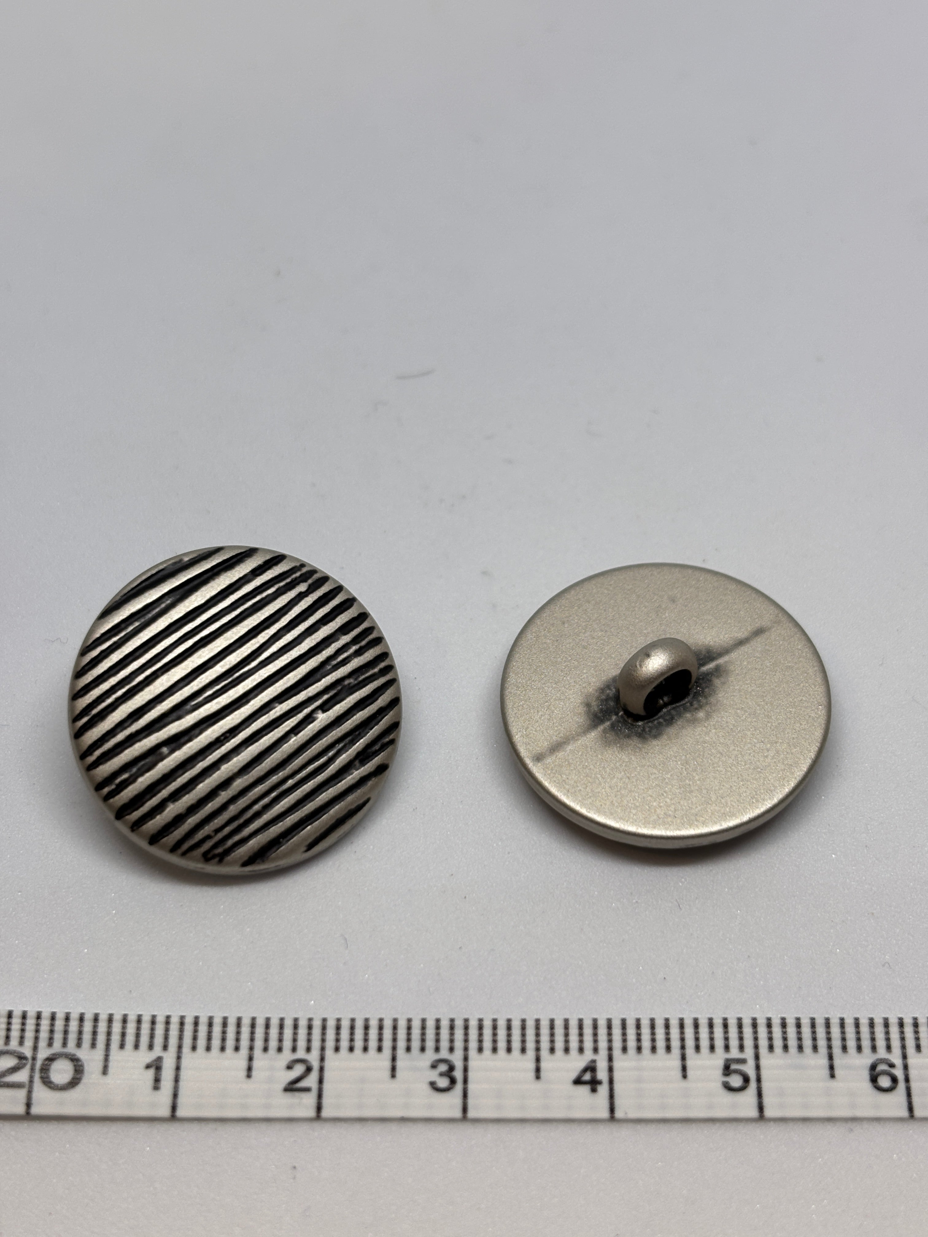 Button B7831 - 18mm (28"), 25mm (40") polyester shank button shown from both sides. boton