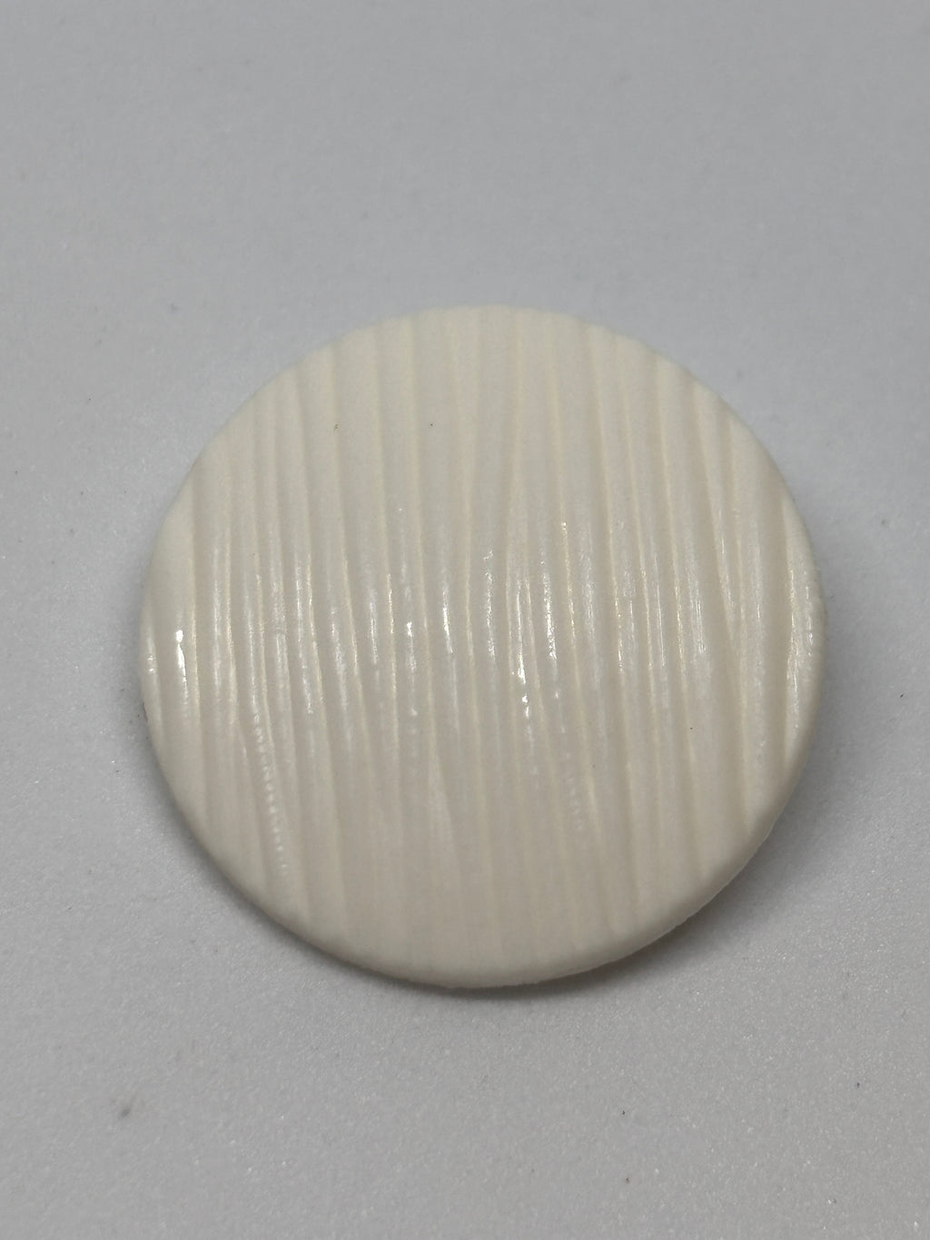 Button B7831 - 18mm (28"), 25mm (40") polyester shank button shown from both sides. boton