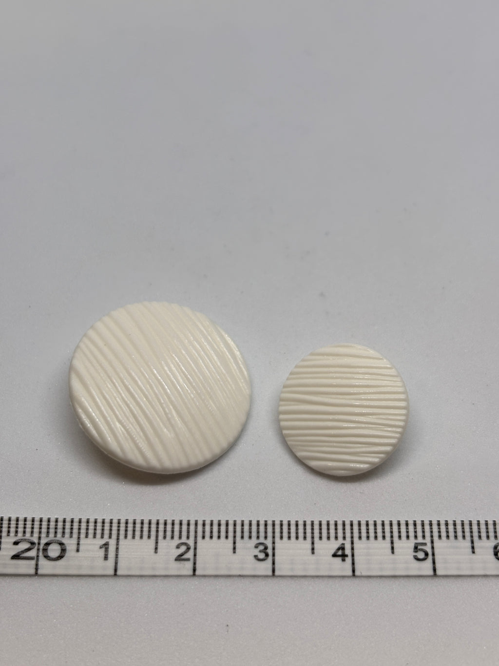 Button B7831 - 18mm (28"), 25mm (40") polyester shank button shown from both sides. boton