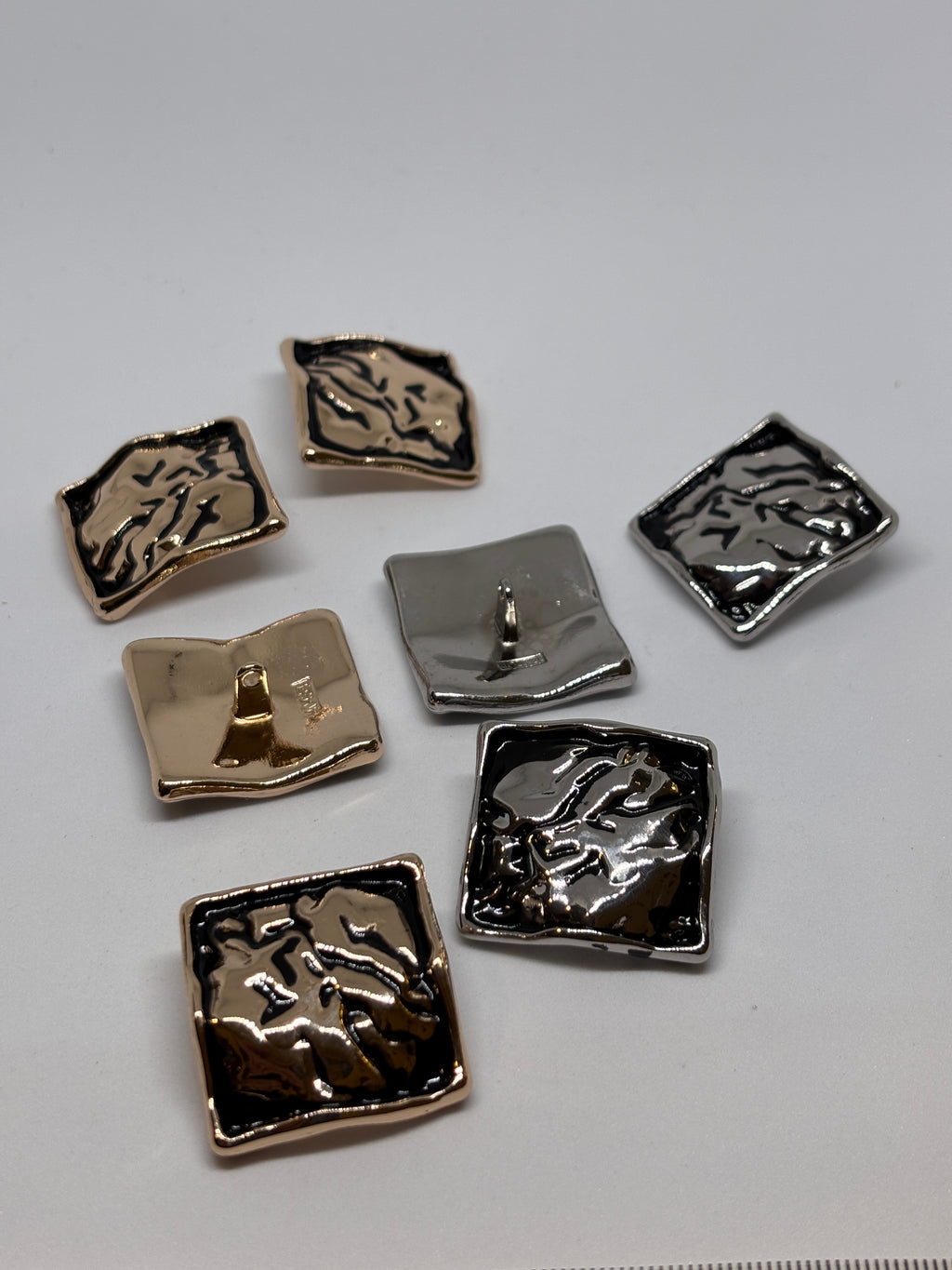Shiny metal buttons in a square shape, showcasing a 32mm (50") shank button design. boton