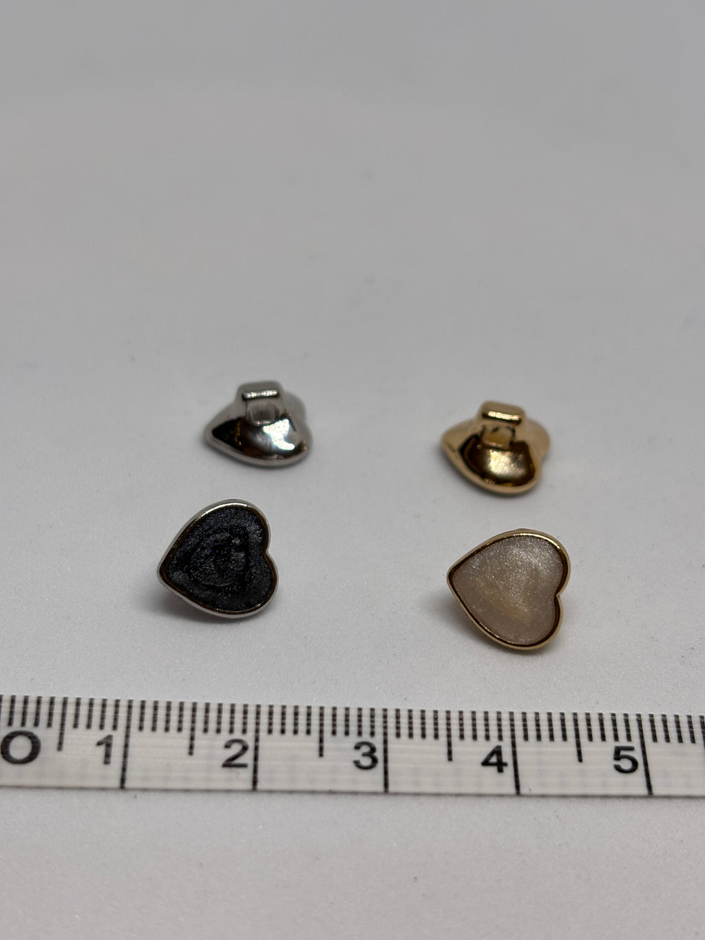 Heart-shaped metal buttons featuring a gold finish, perfect for sewing and craft projects, showcasing the elegance of a button. boton