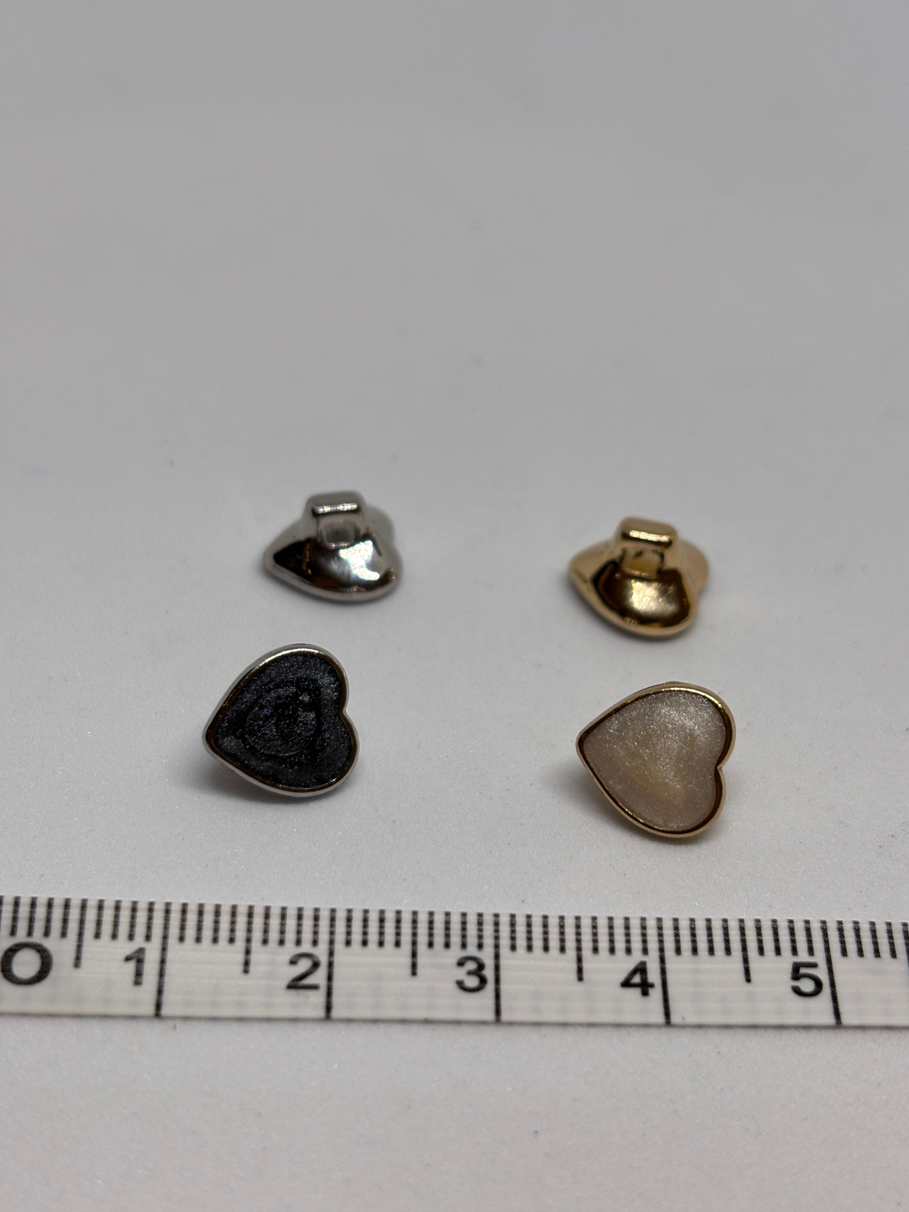 Heart-shaped metal buttons featuring a gold finish, perfect for sewing and craft projects, showcasing the elegance of a button. boton
