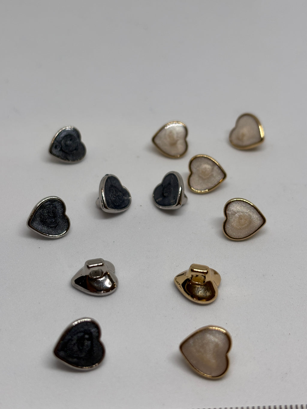 Heart-shaped metal buttons featuring a gold finish, perfect for sewing and craft projects, showcasing the elegance of a button. boton